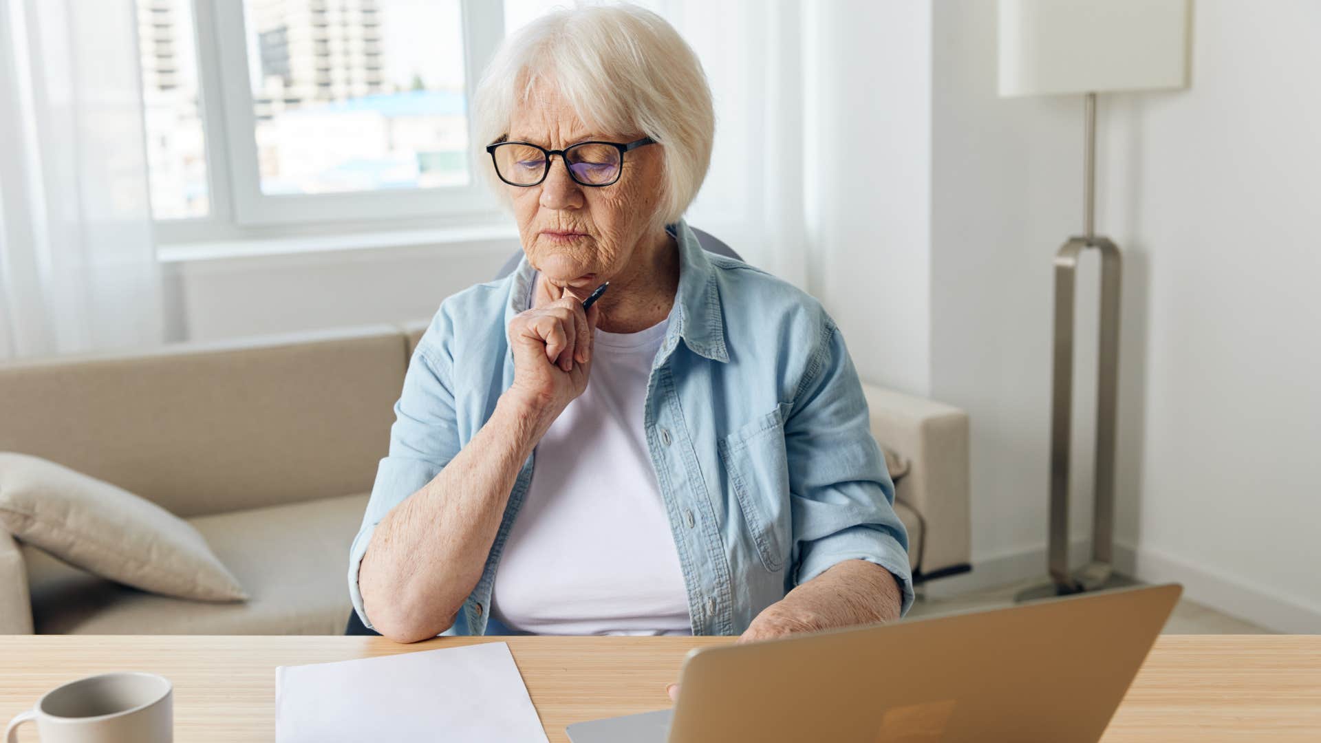 Woman balancing a checkbook by hand at home.