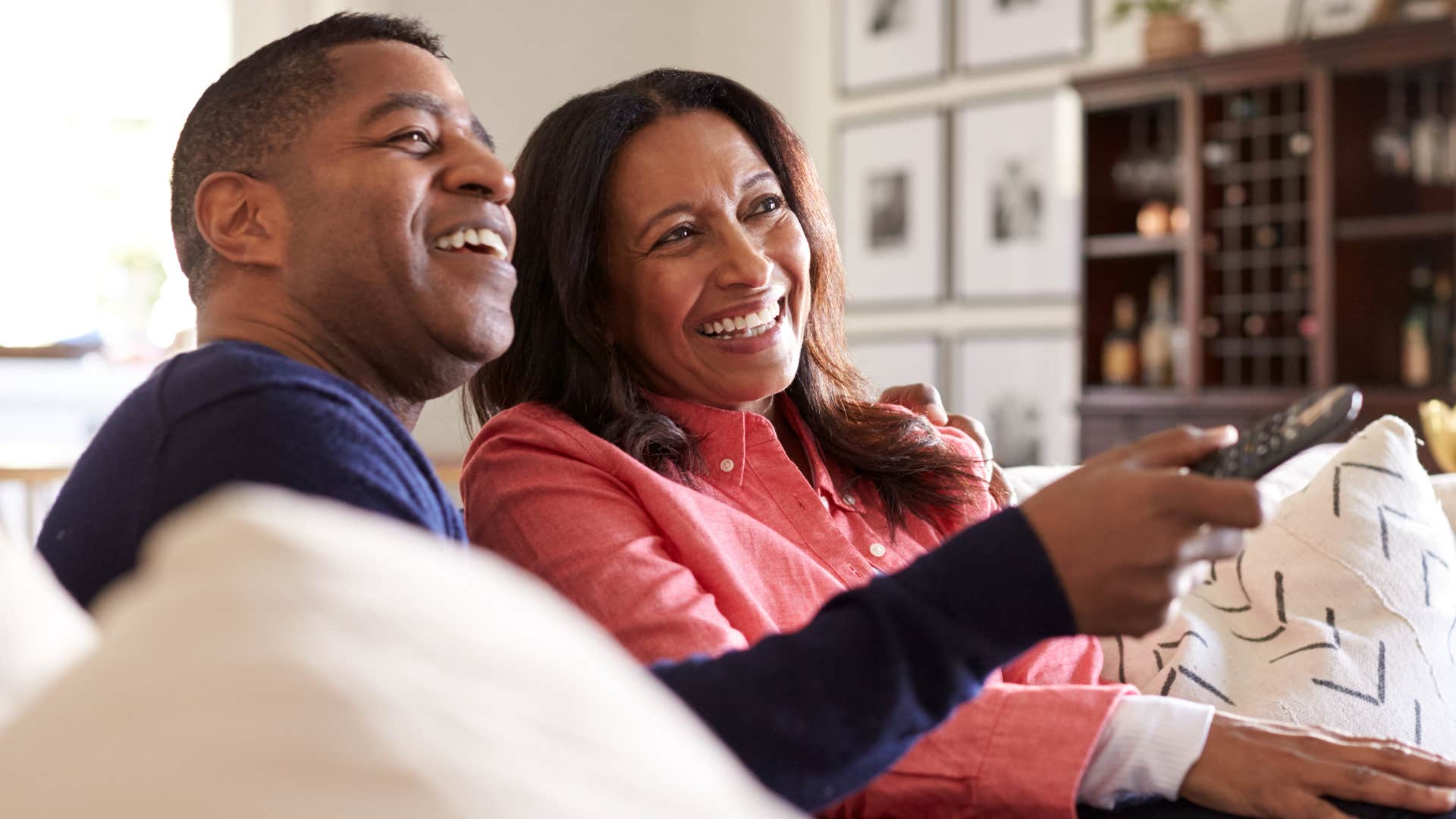Middle-aged couple watching cable TV on the couch.
