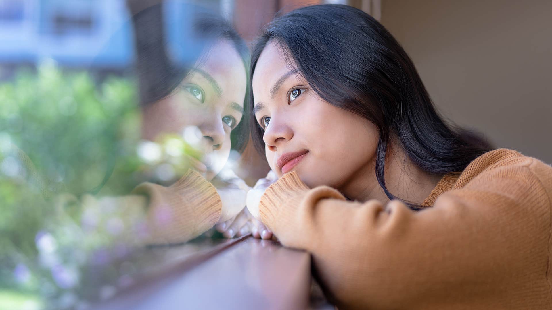 Woman daydreaming while looking out a window.