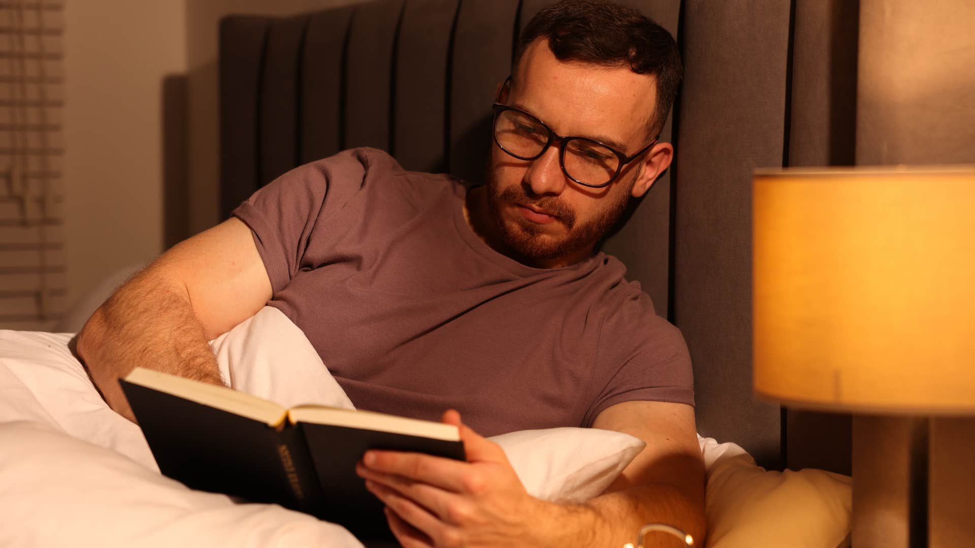 Man with high intelligence reading in bed at night.