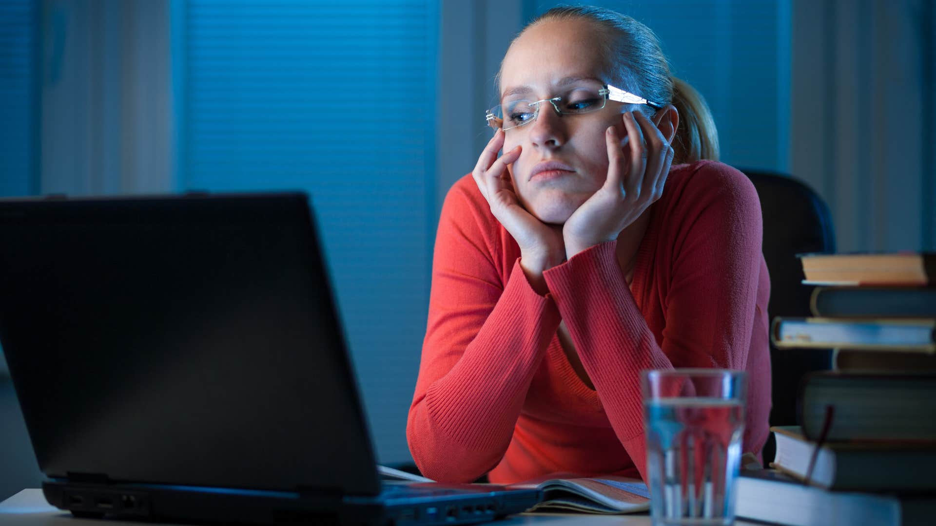 Woman with procrastination habits looking at her computer at night.