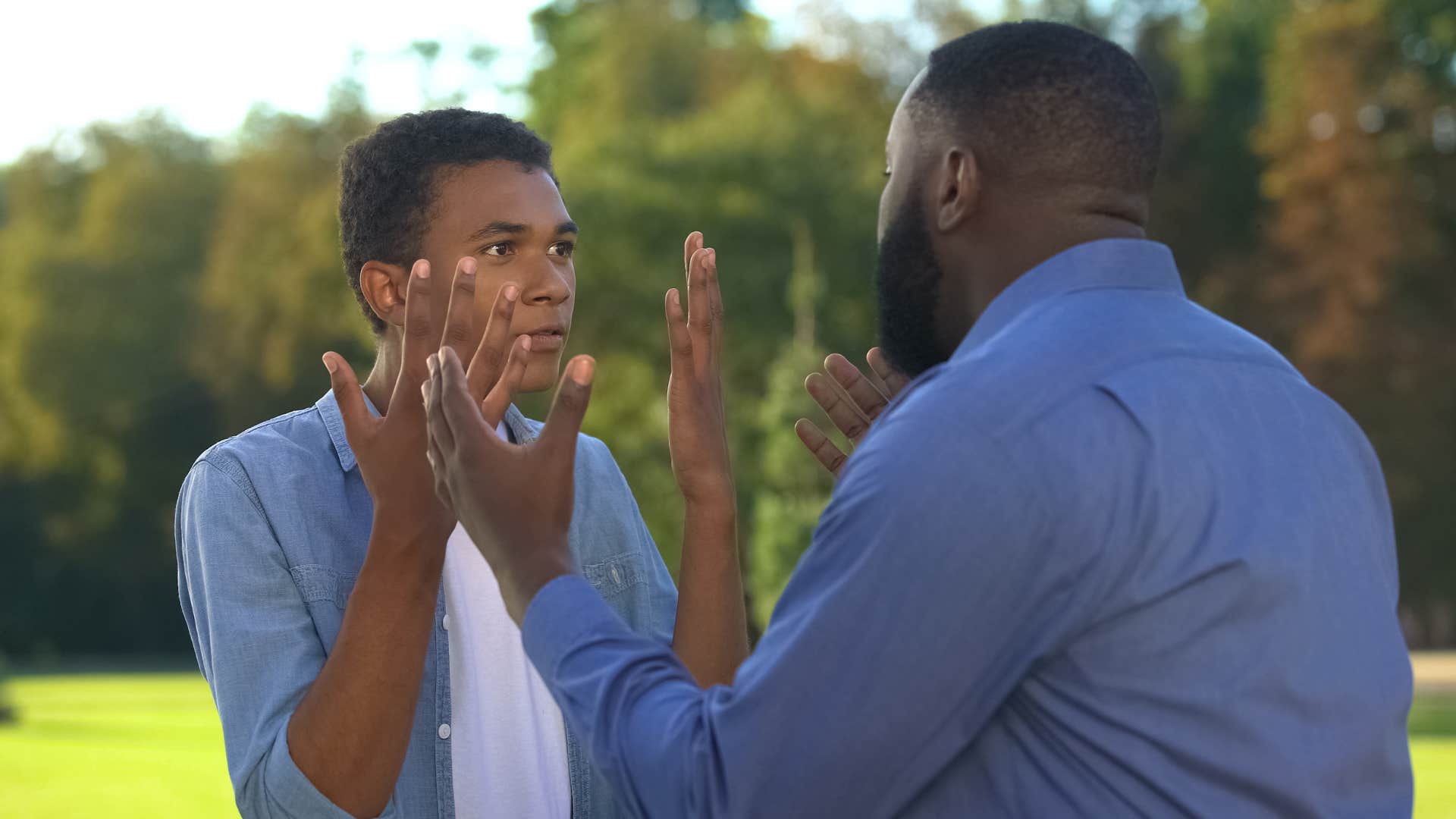 teenage son in blue blaming others for everything as he argues with father