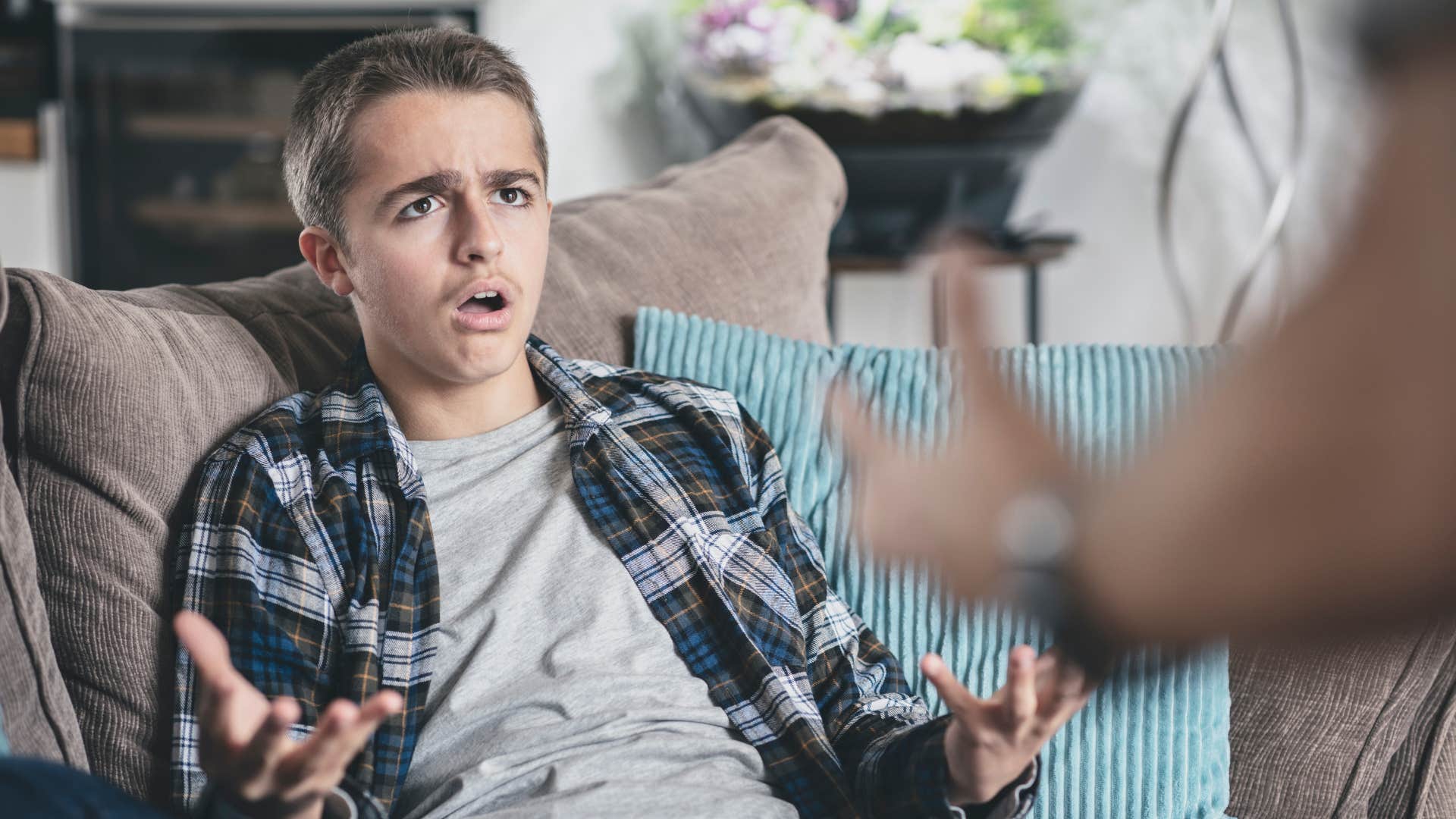 teenage boy looking mad as he talks back to his parent