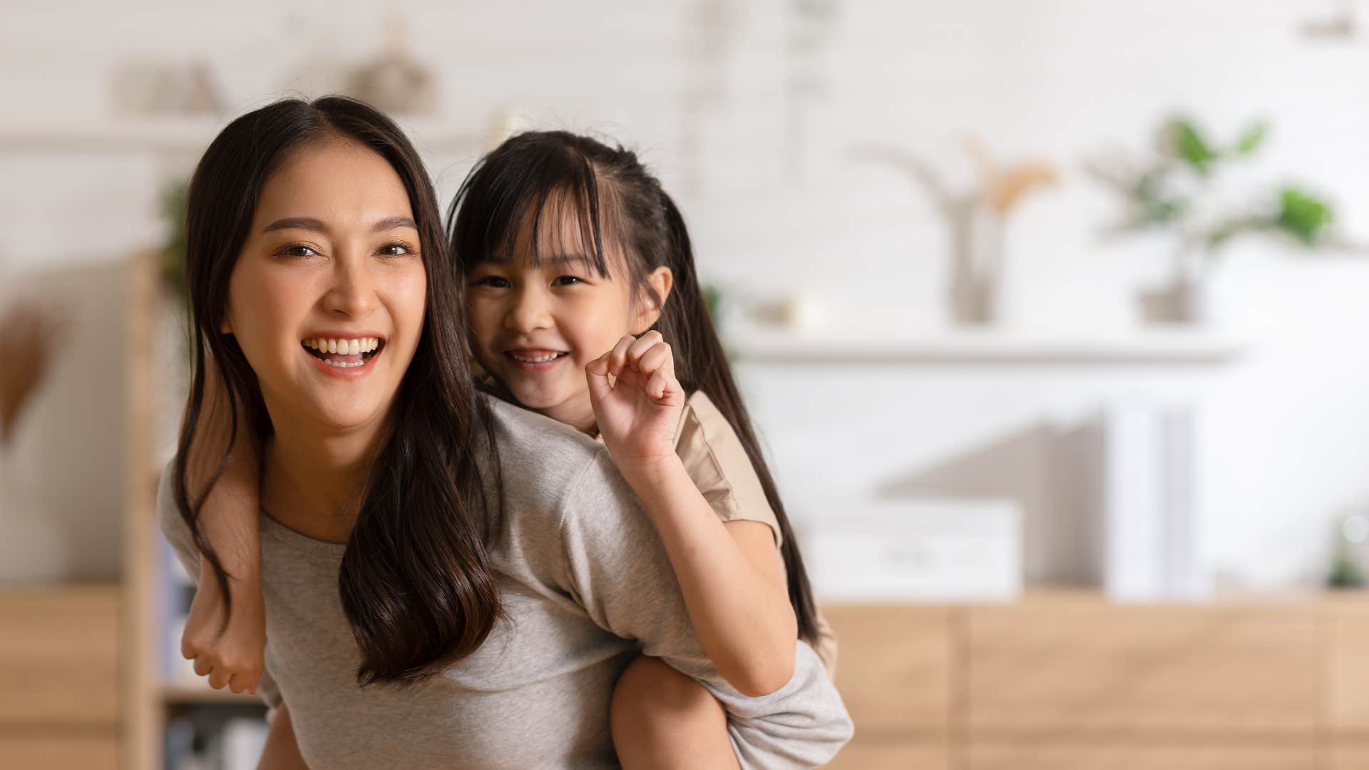 happy single mom giving daughter a piggyback ride