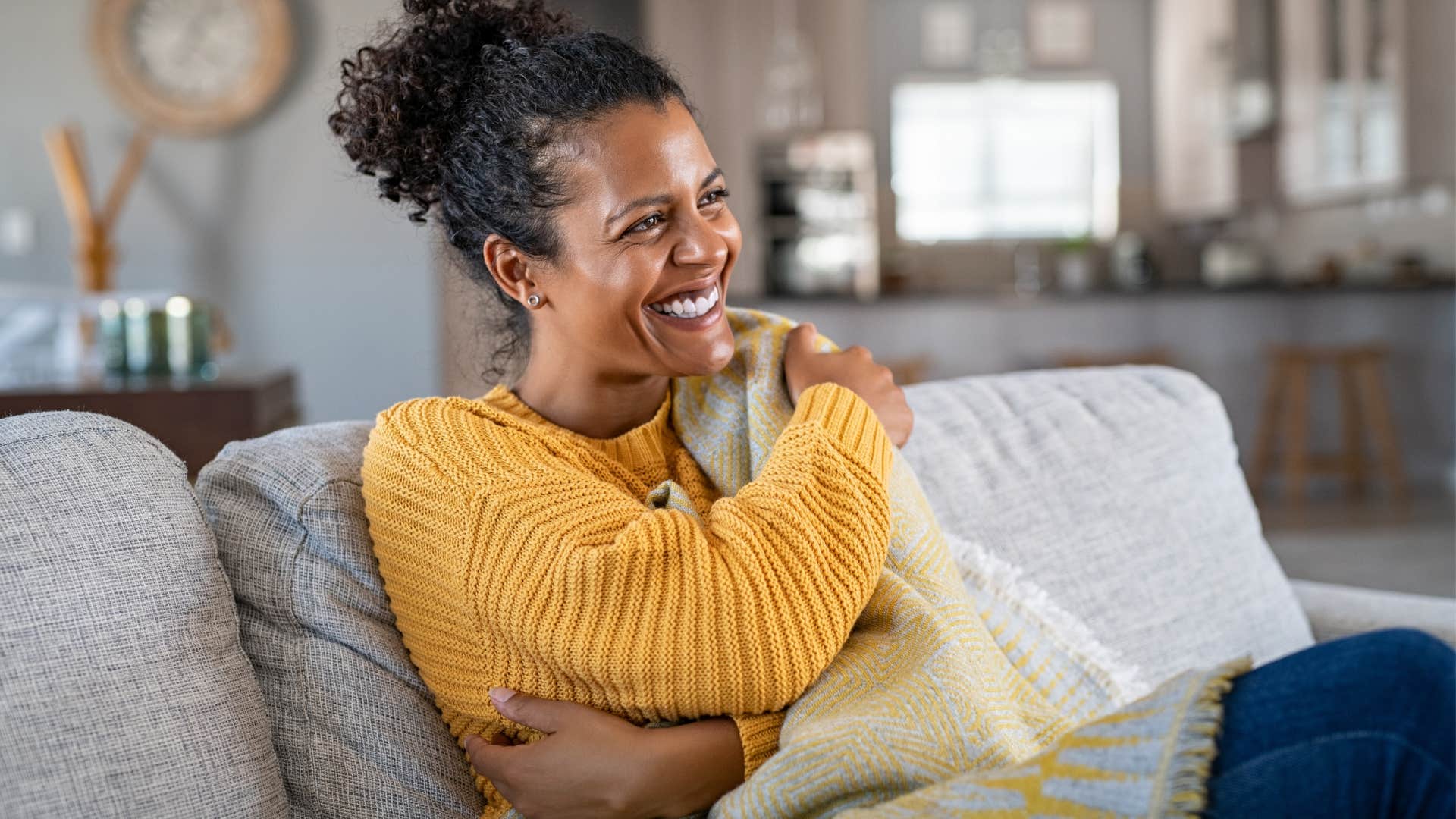 Woman smiling and holding extra blankets and pillows.