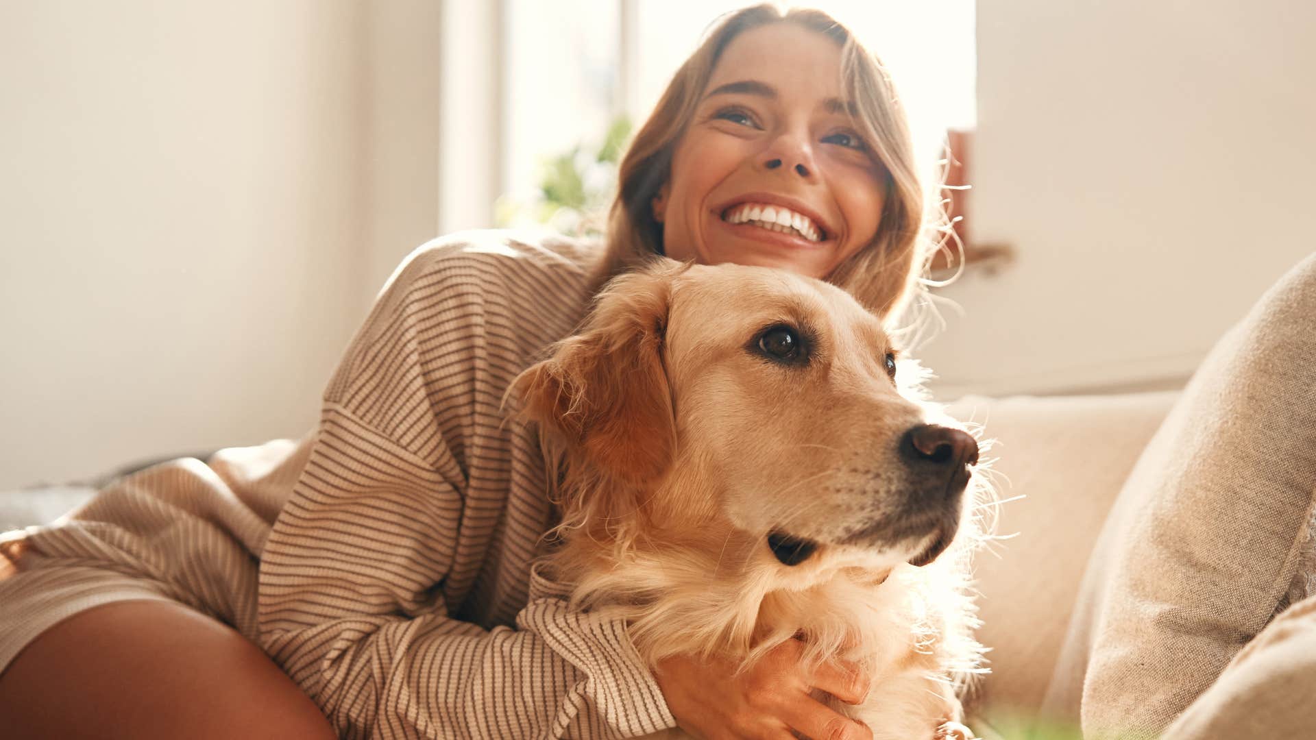 Man smiling and hugging her pet at home.