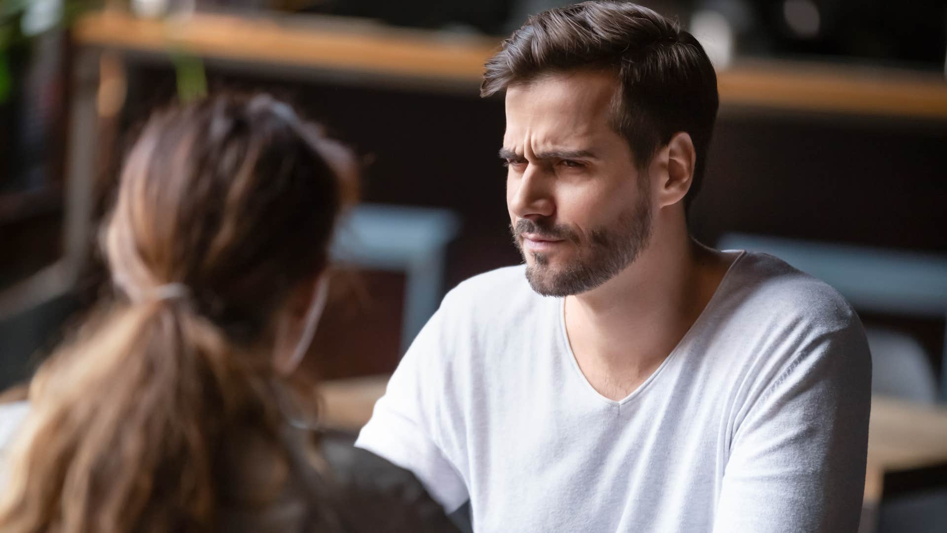 man looking confused as he thinks you're imagining things as he sits across from woman