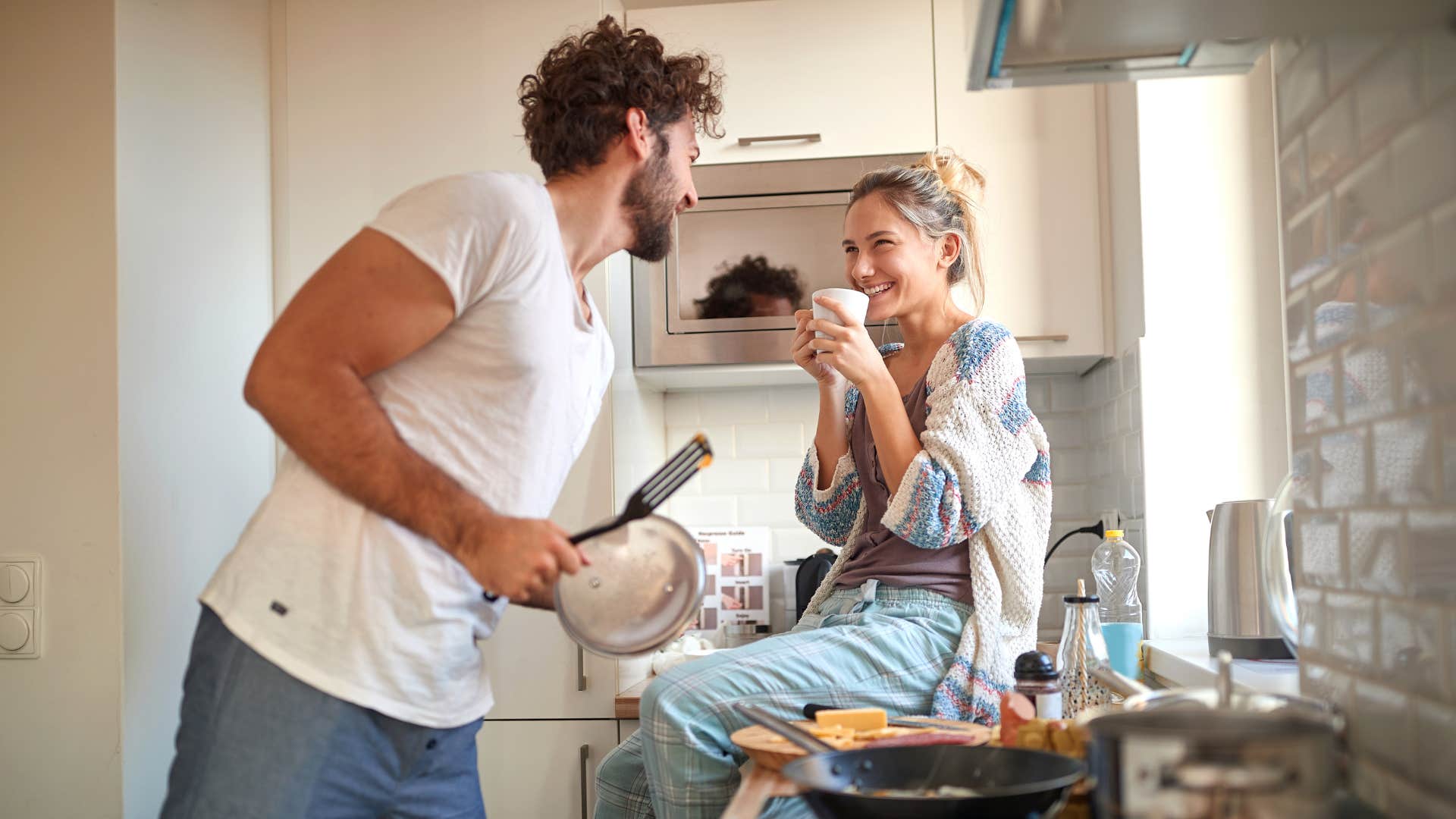 husband making food for wife sitting on kitchen counter