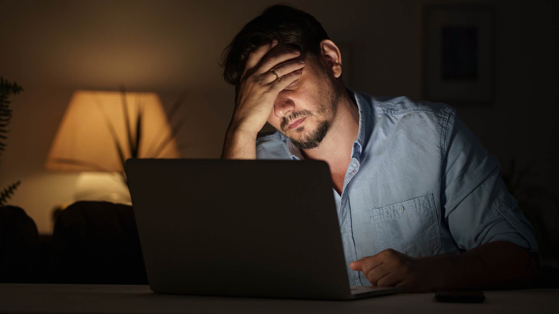 Man who can prioritize work looking tired on his laptop at home.