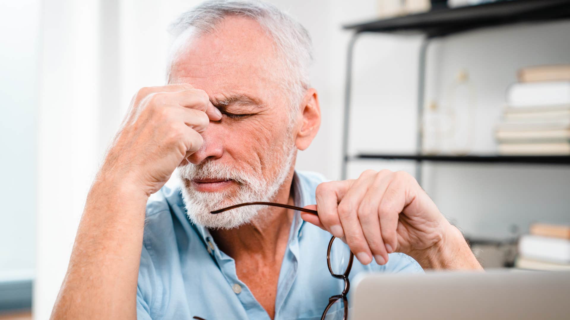 Man who's emotionally burnt out holding his head.