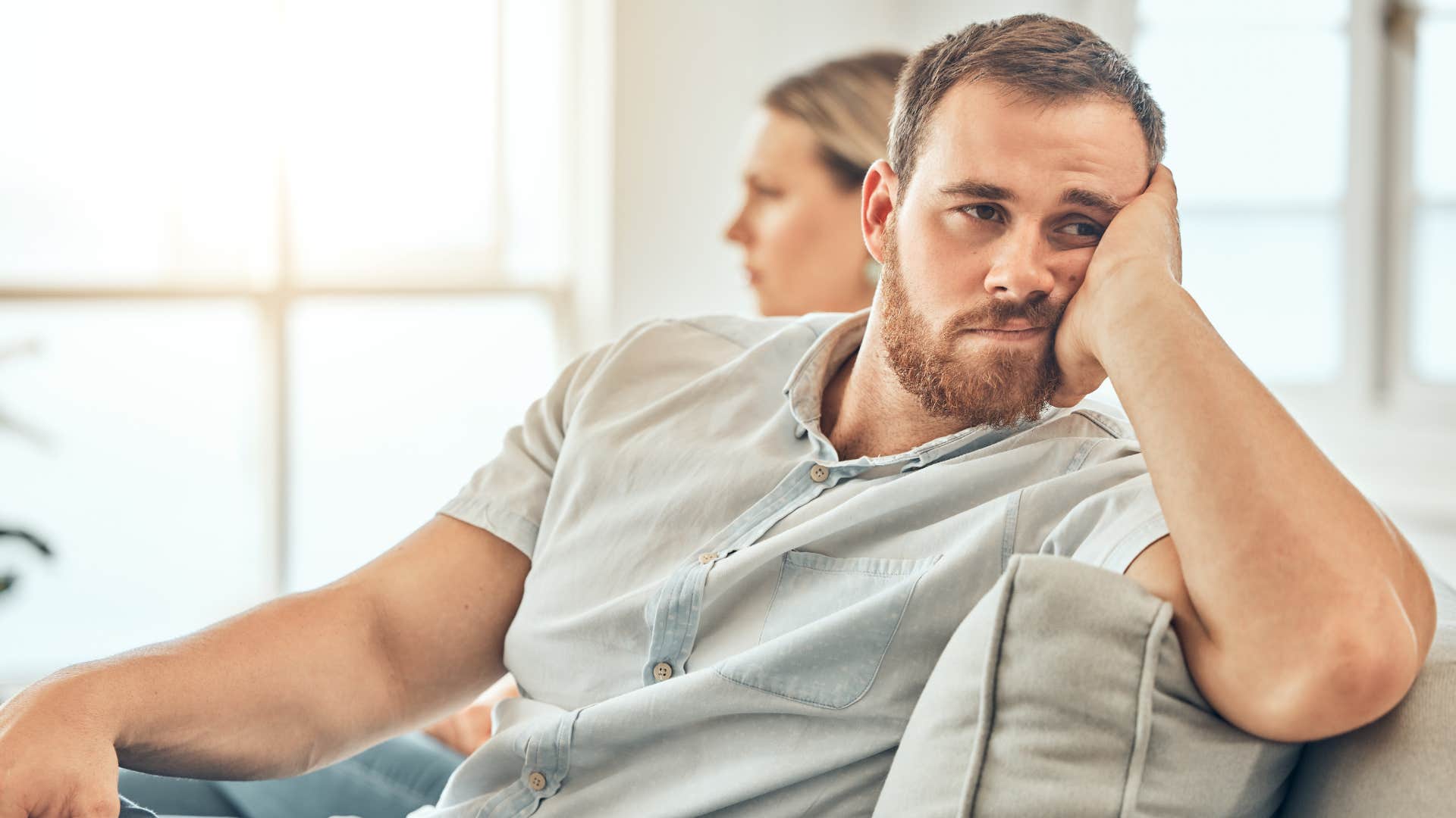 Upset couple who feels like roommates sitting on the couch.