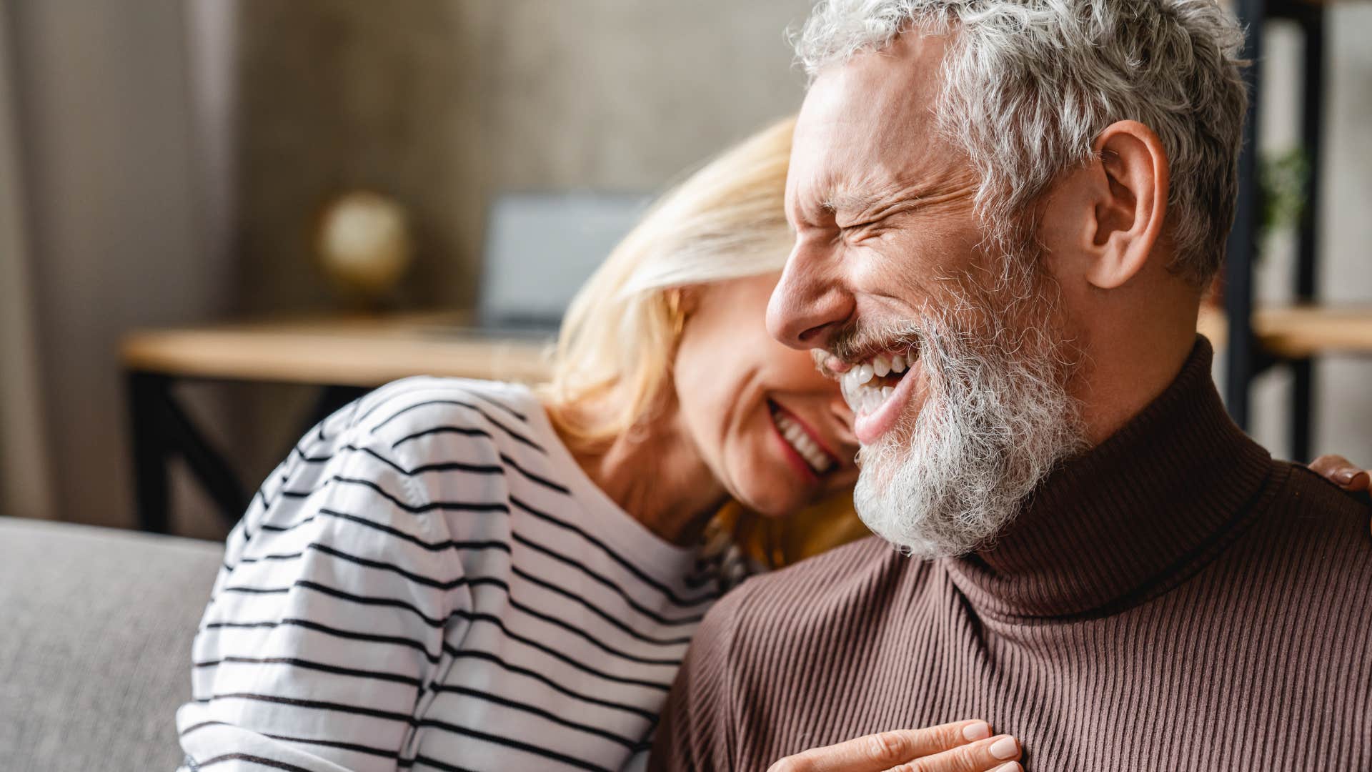 Couple who laughs often hugging at home.