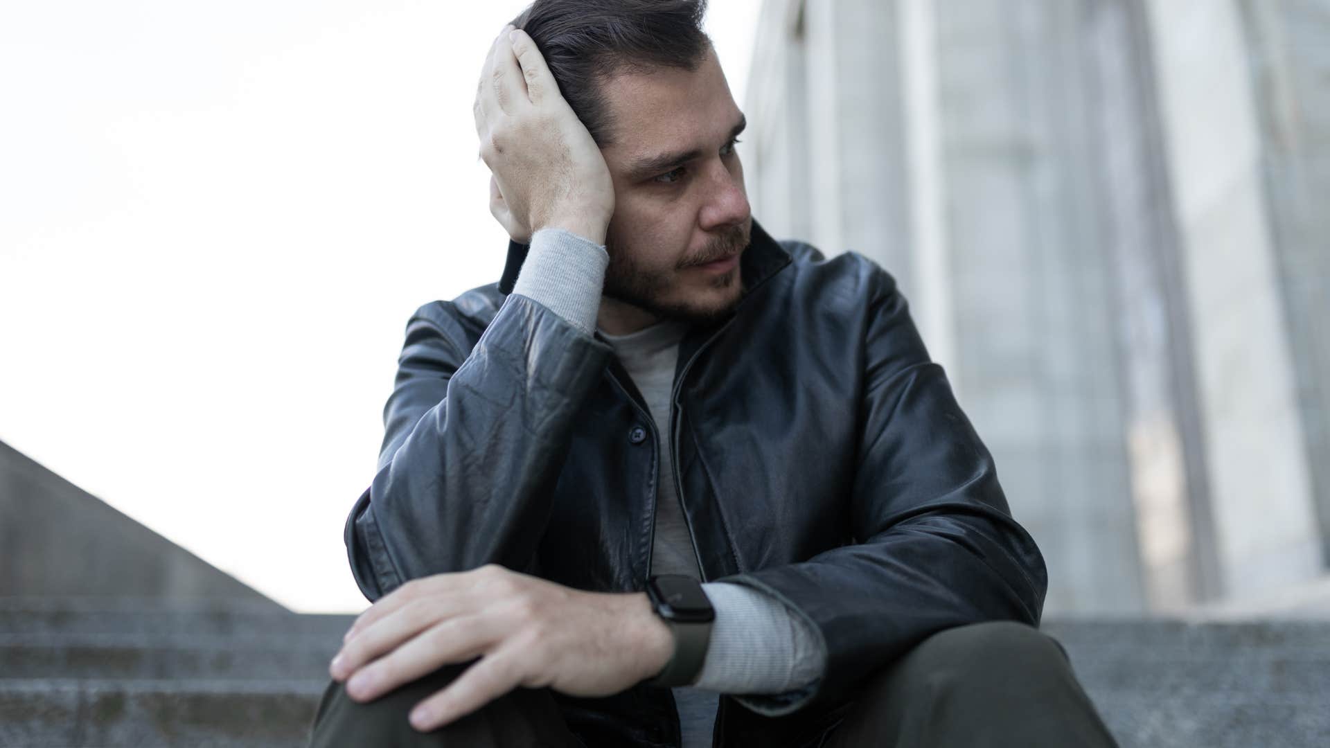 emotional man sitting outside