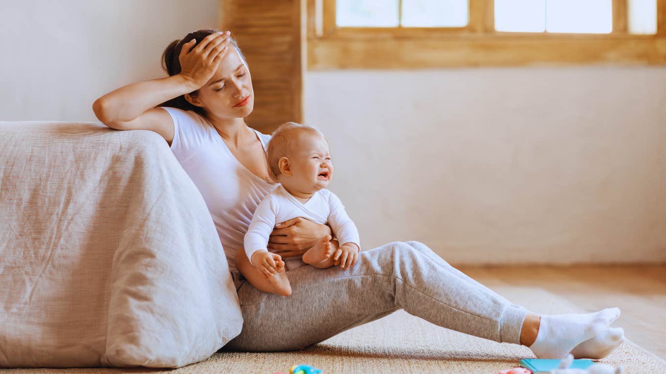 stressed out mom holding baby sitting on floor