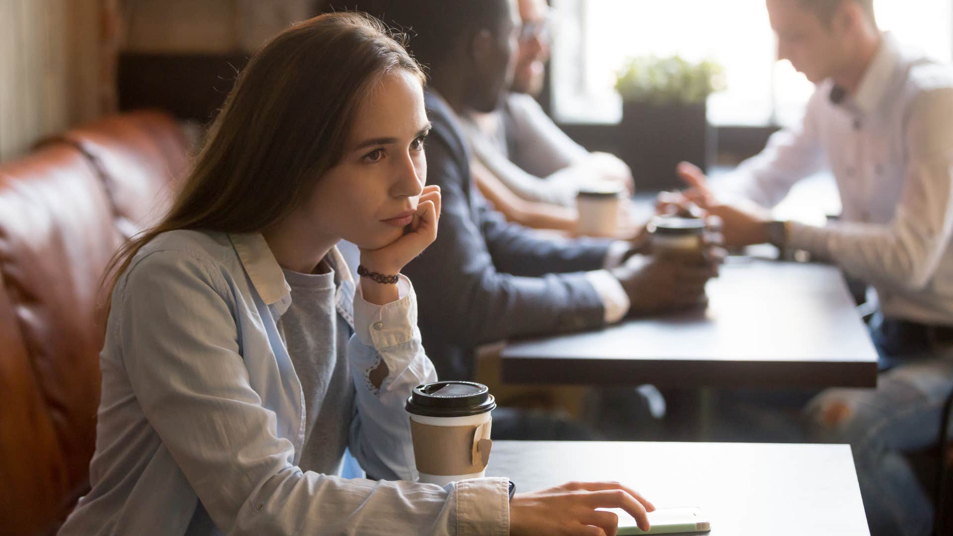 woman being left out of plans as she enjoys coffee alone