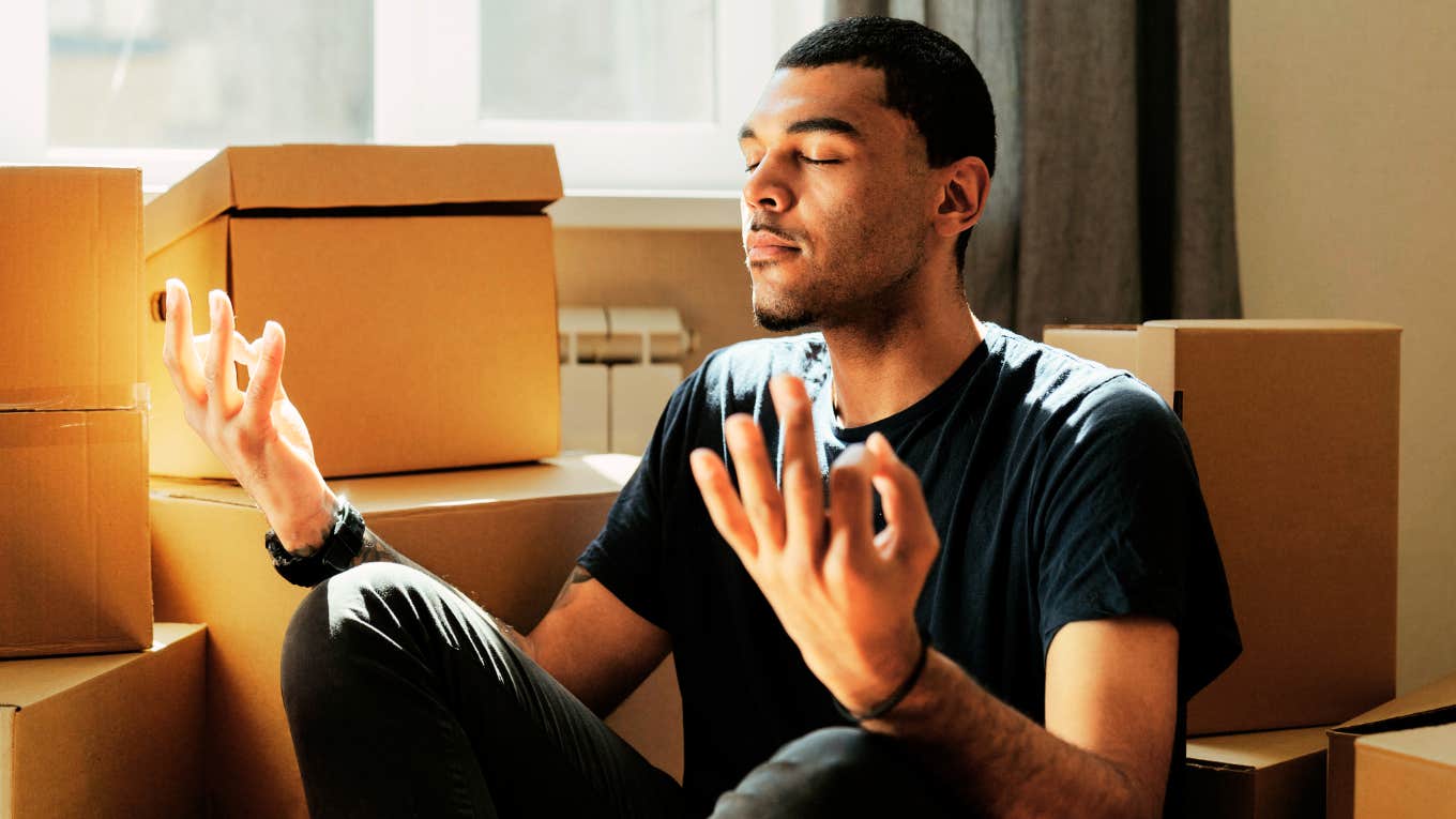 Man meditating quickly while unpacking. 