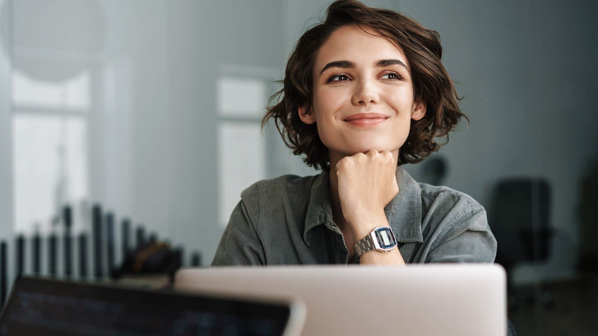 woman is competitive as she dreams off while sitting in front of laptop
