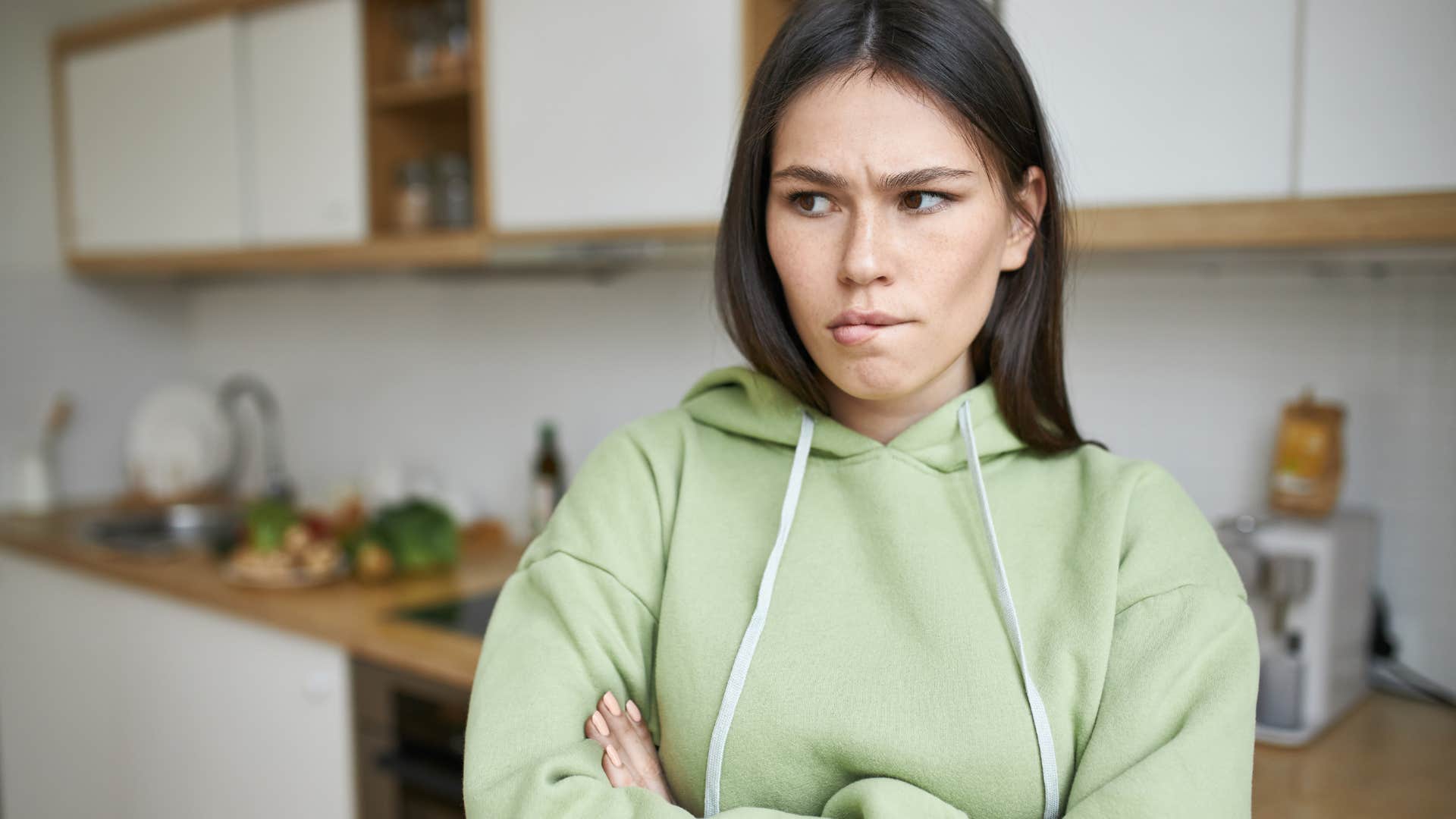 woman in green hoodie being stubborn in a cute way as she pouts