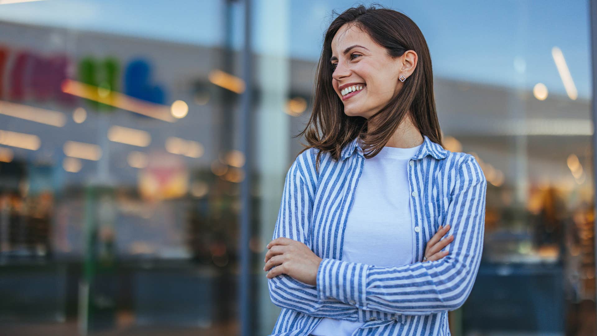 woman in stripped jacket and white shirt switching moods quickly as she crosses arms