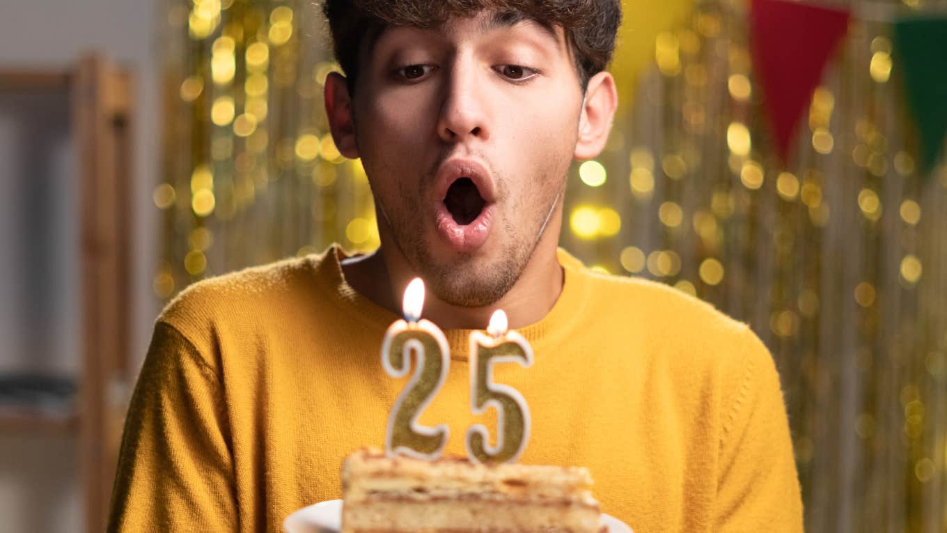 man blowing out the candles on a birthday cake