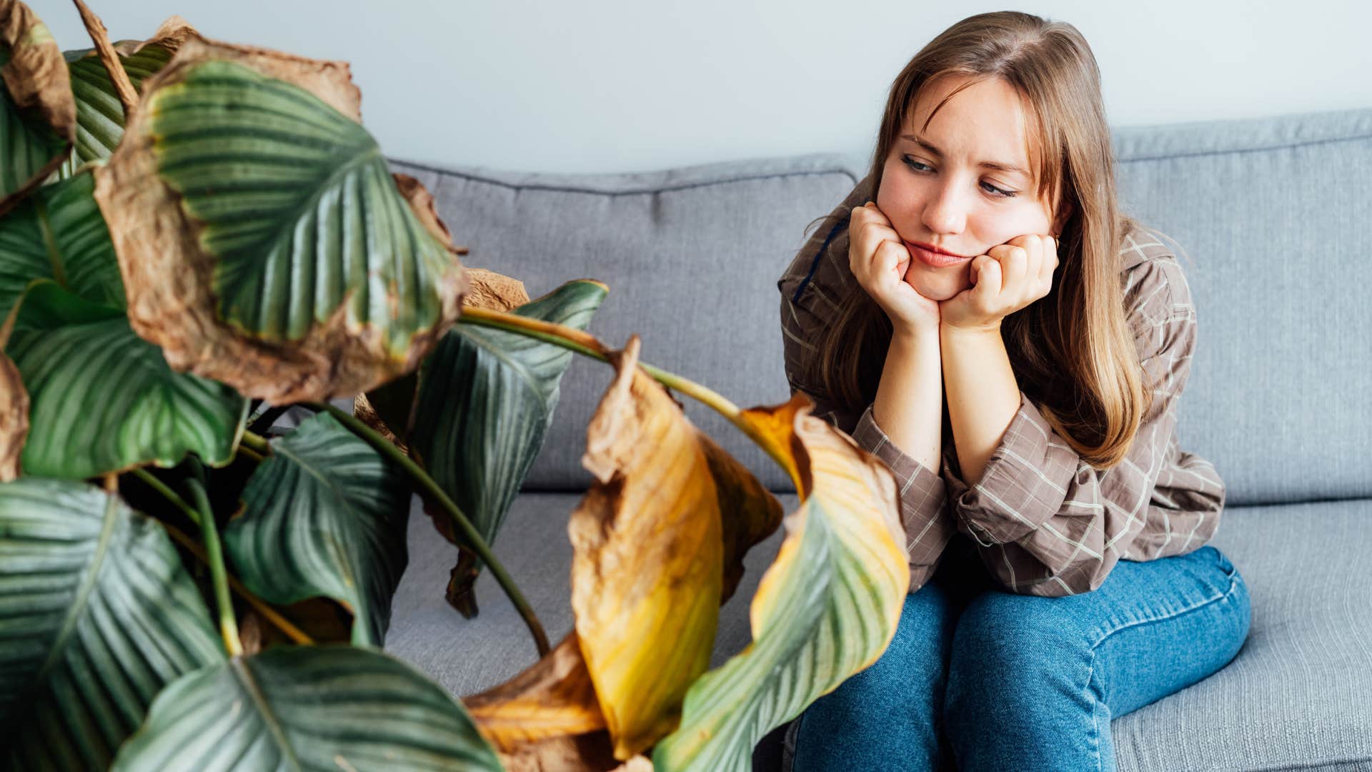 woman looking upset sitting next to dead plants