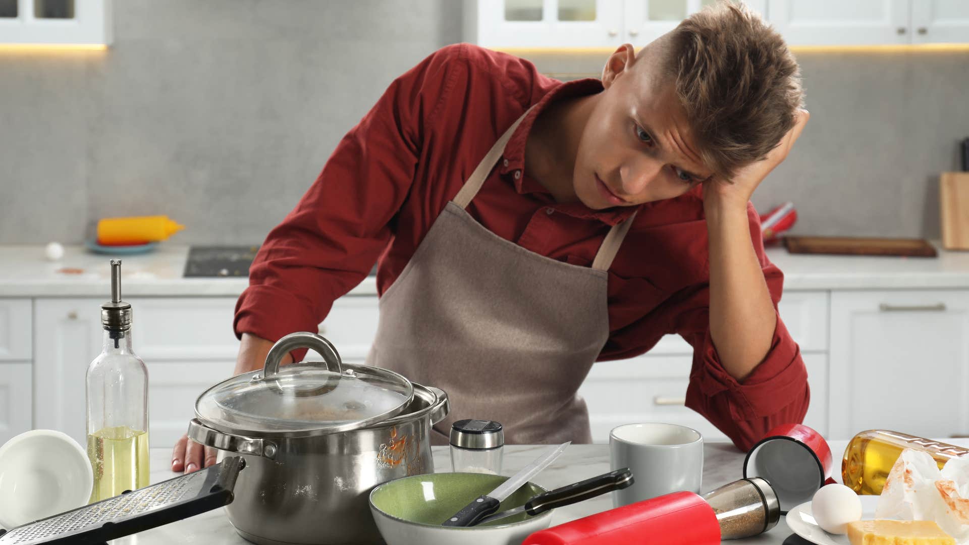man looking at dirty dishes in his kitchen