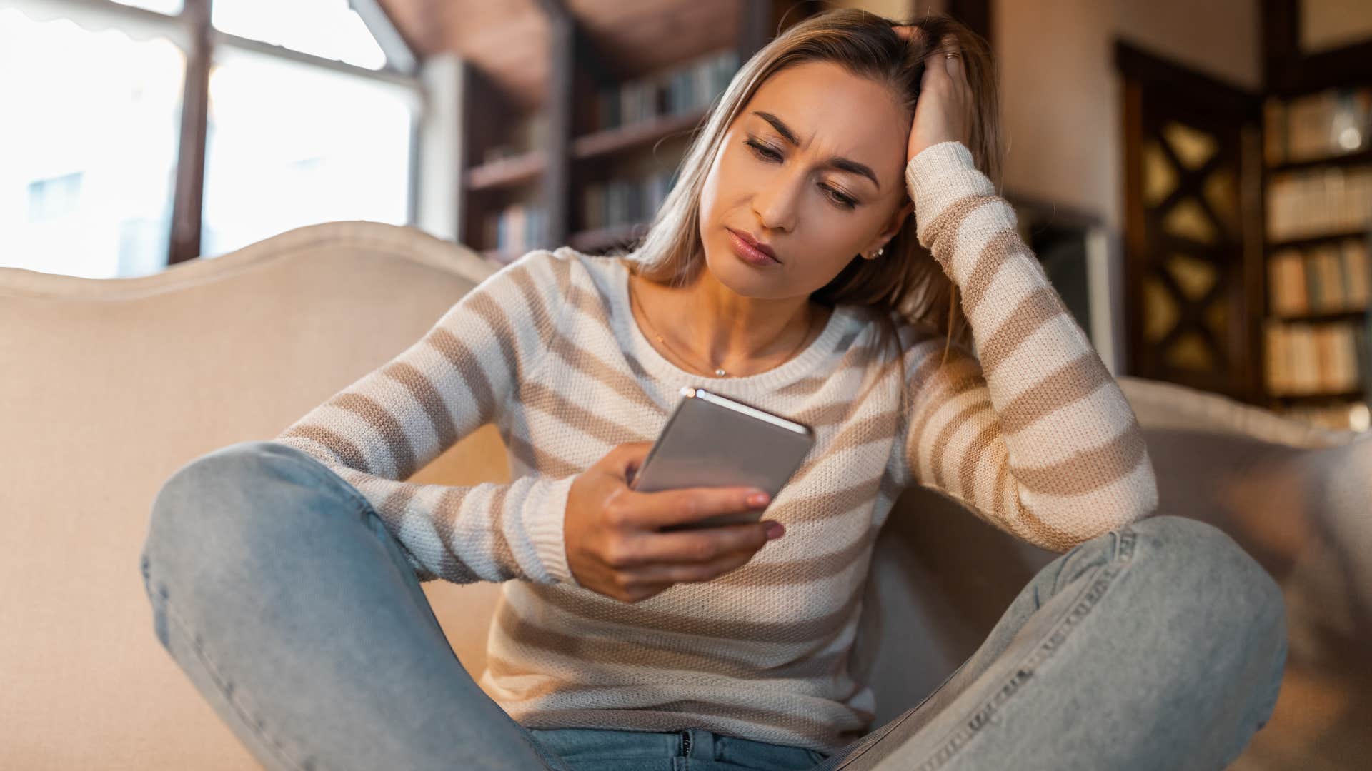 upset woman sitting on her couch surrounded by trendy decor