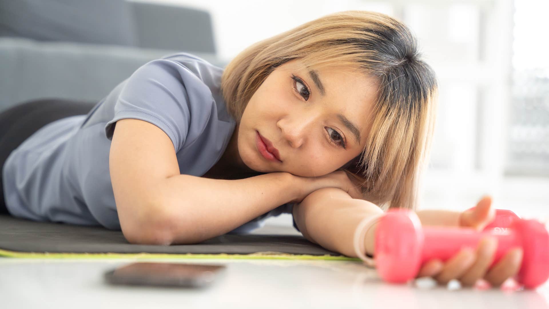woman holding unused workout equipment in her living room