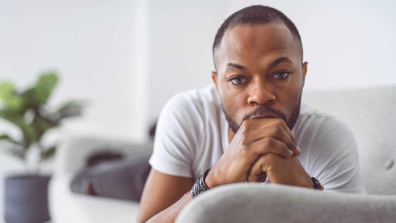 extremely unhappy man sitting on his couch moping