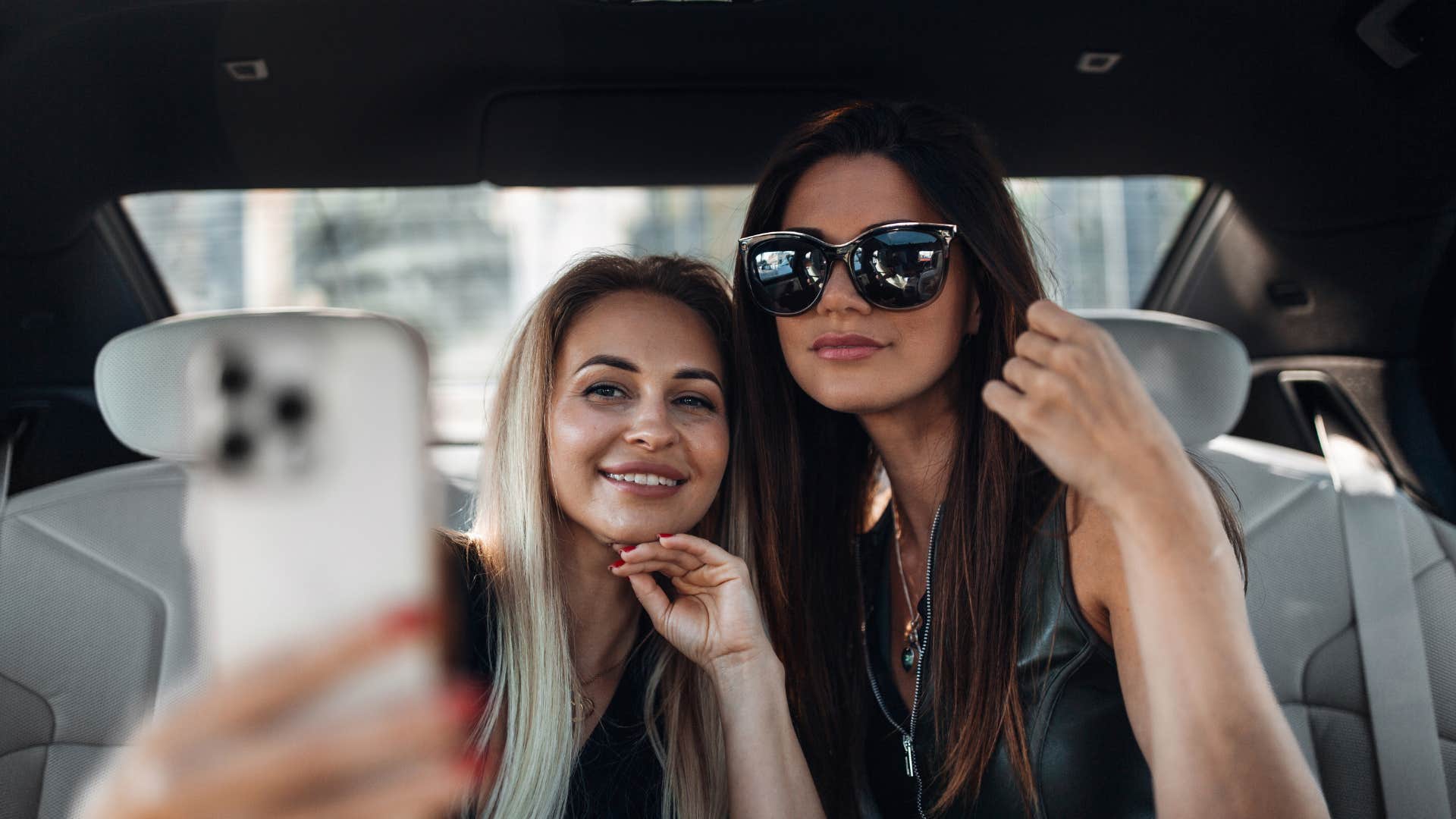 two friends taking photo of themselves in backseat