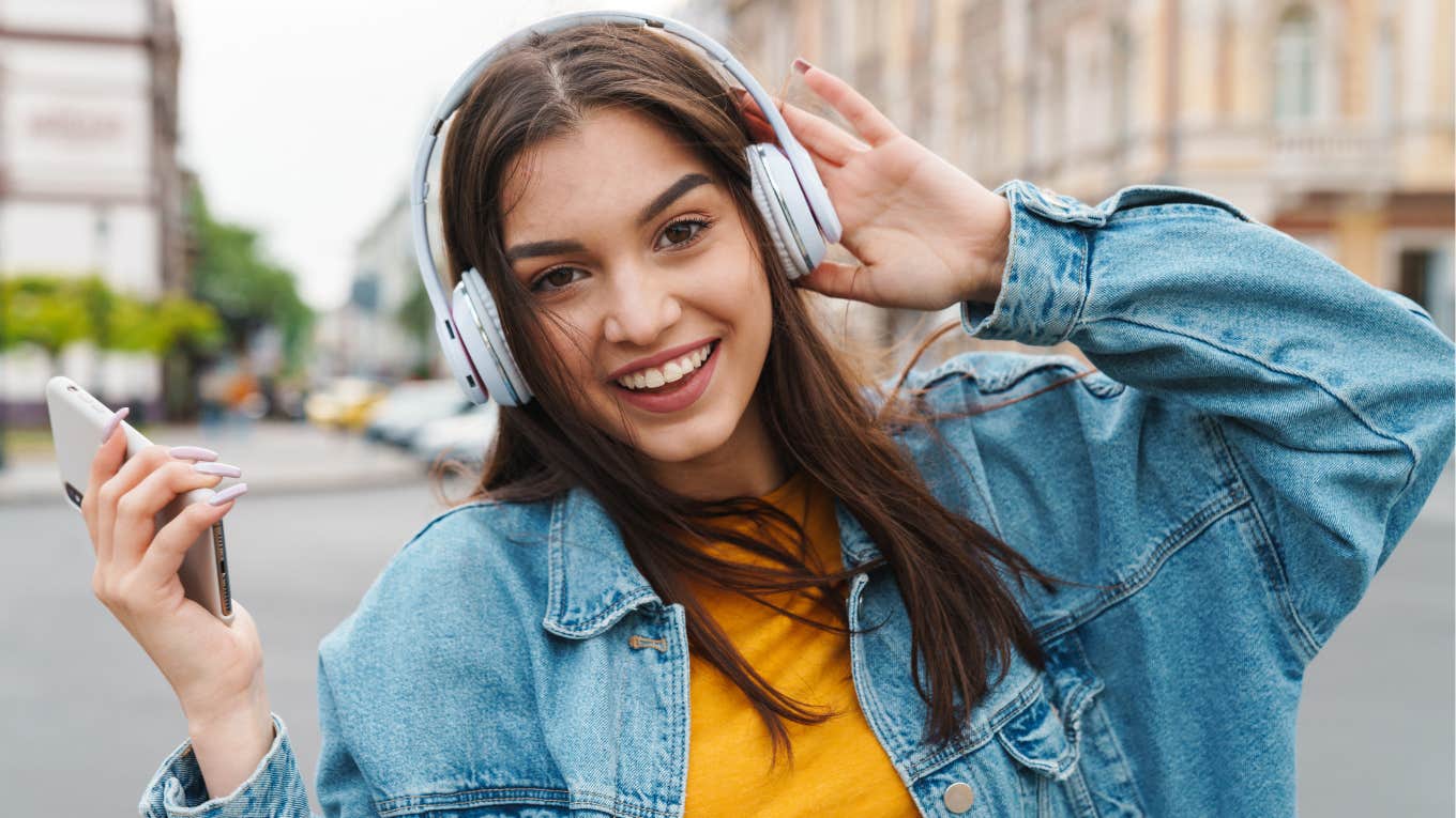 People Over 40 Think Gen Z Is Odd For Doing These Everyday Things young gen z girl wearing headphones and holding phone