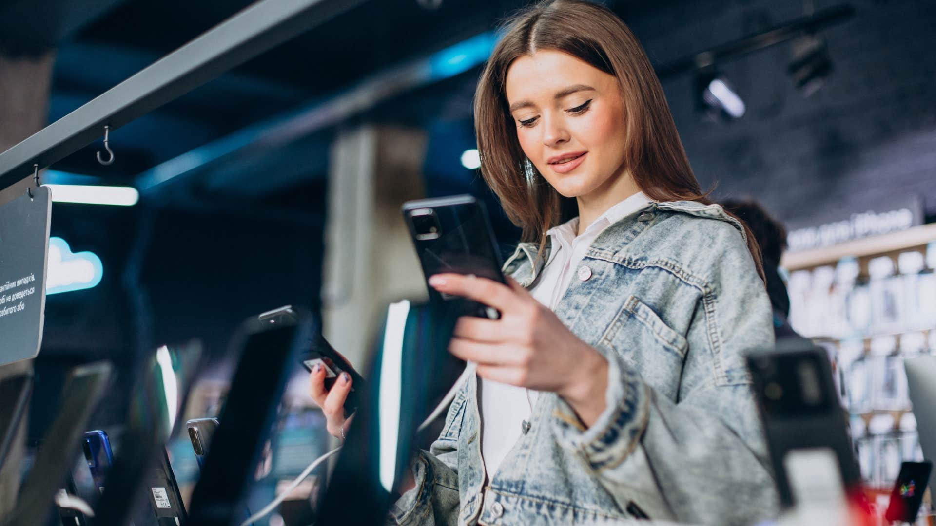 Woman looking at phones with extended warranties in a store.