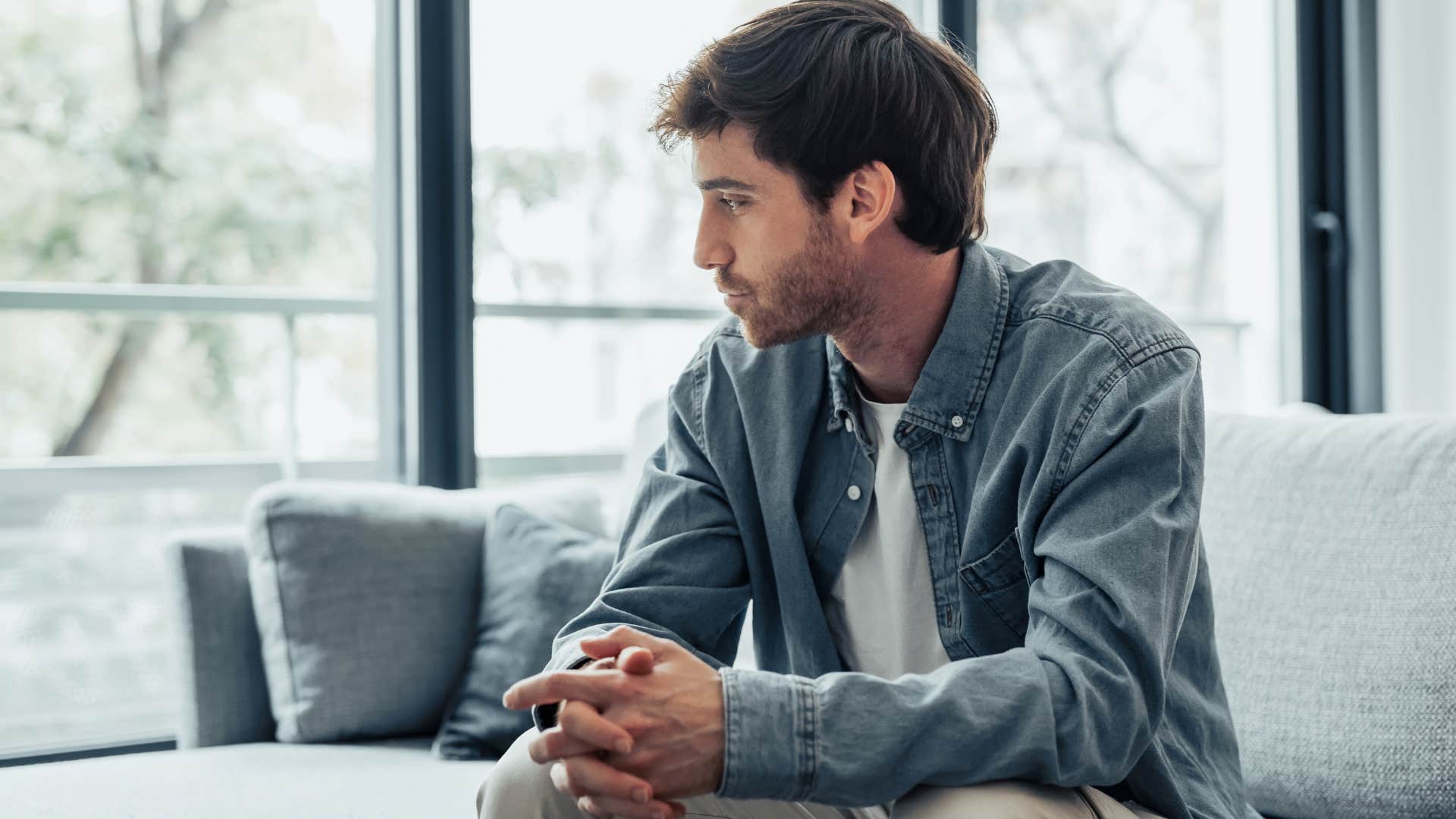 man holding in his emotions sitting on the couch