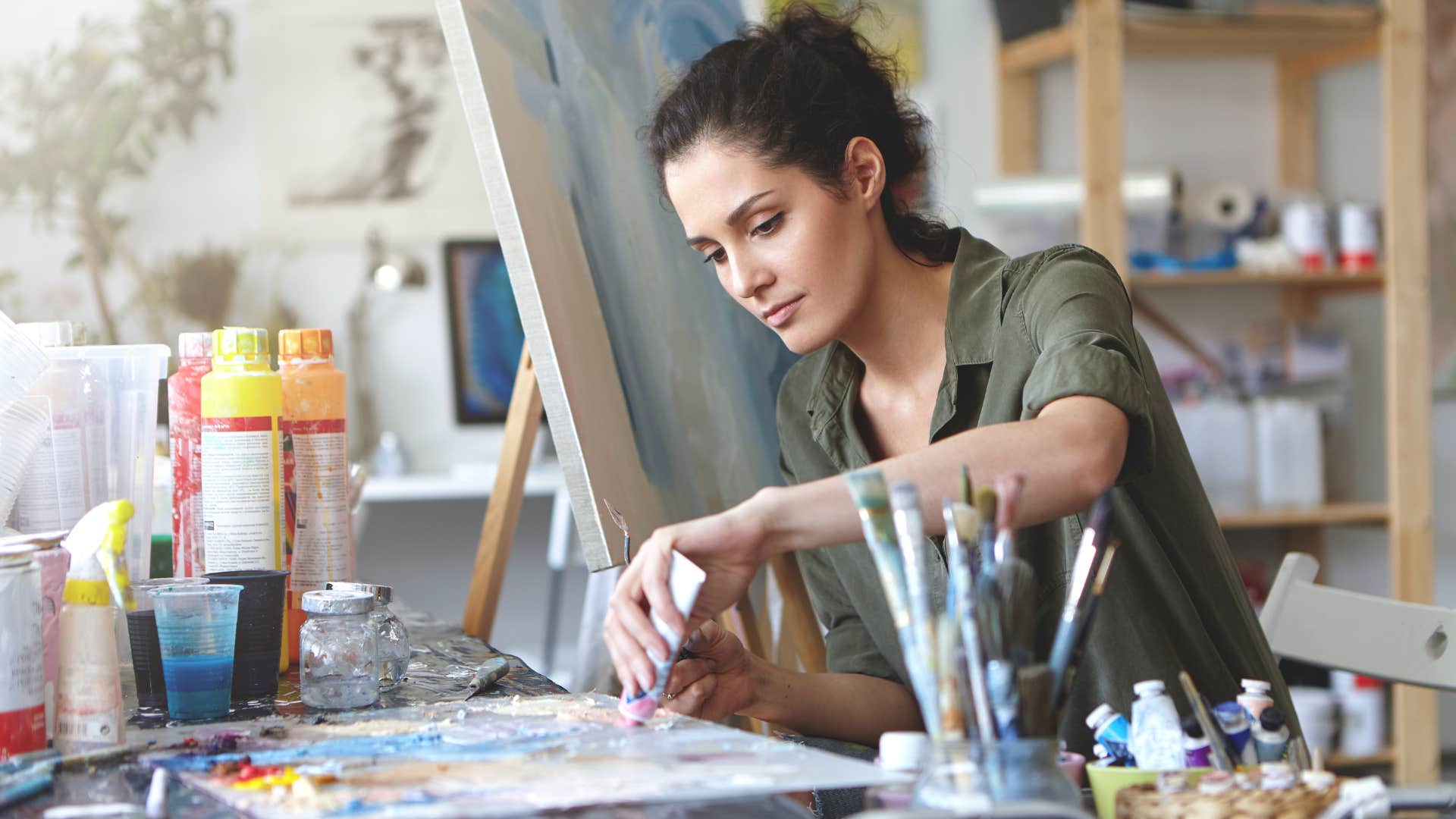 happy woman being creative painting a canvas