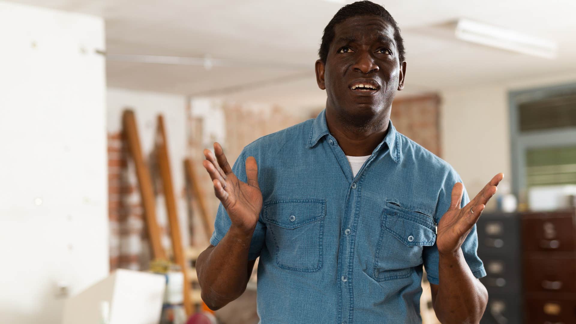 man looking shocked surrounded by clutter at home
