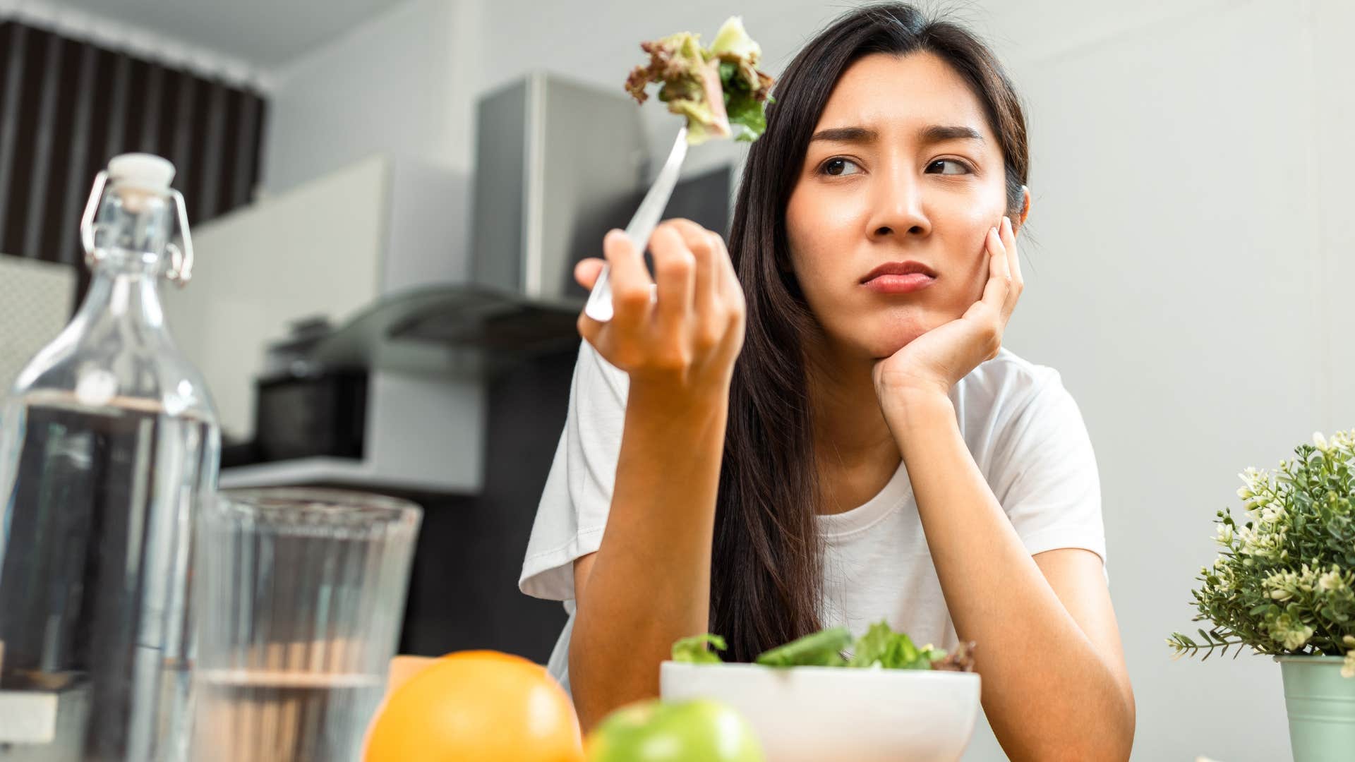 woman glaring at silverware while eating