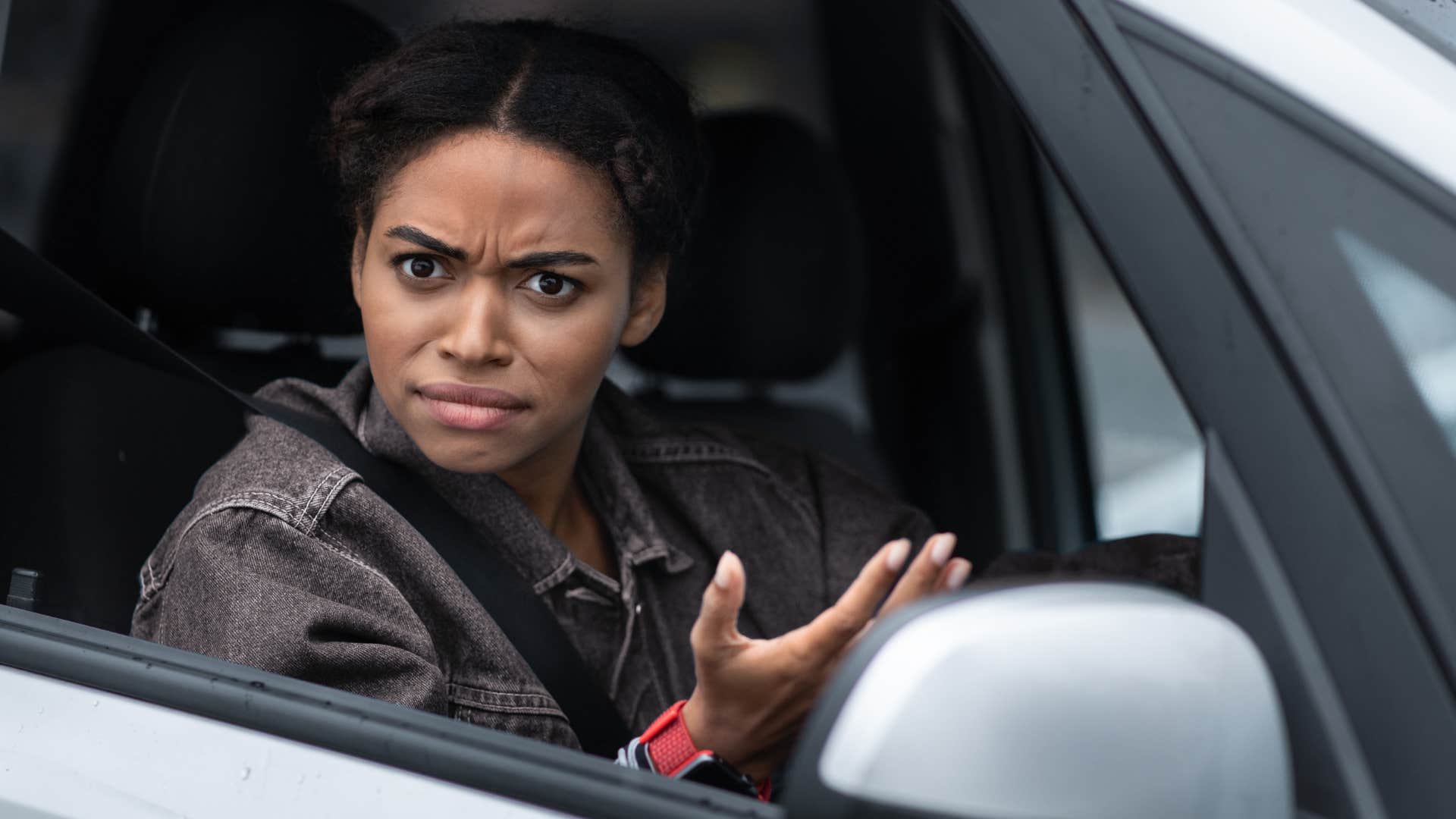 Woman looking upset in her car after breaking rules.