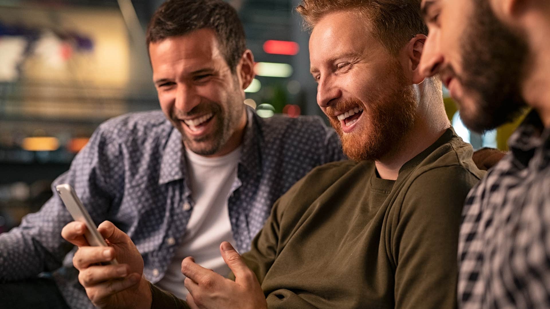 Men laughing at low-brow humor on a phone.