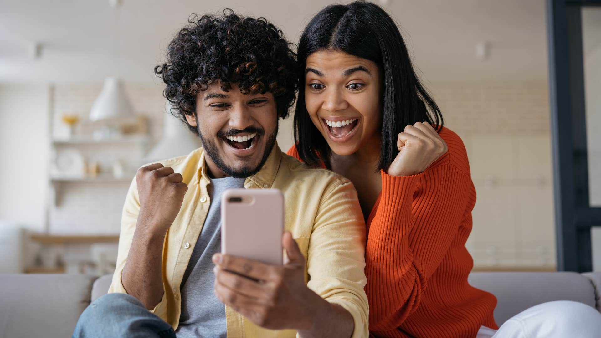 Couple smiling and playing luck-based games at home.
