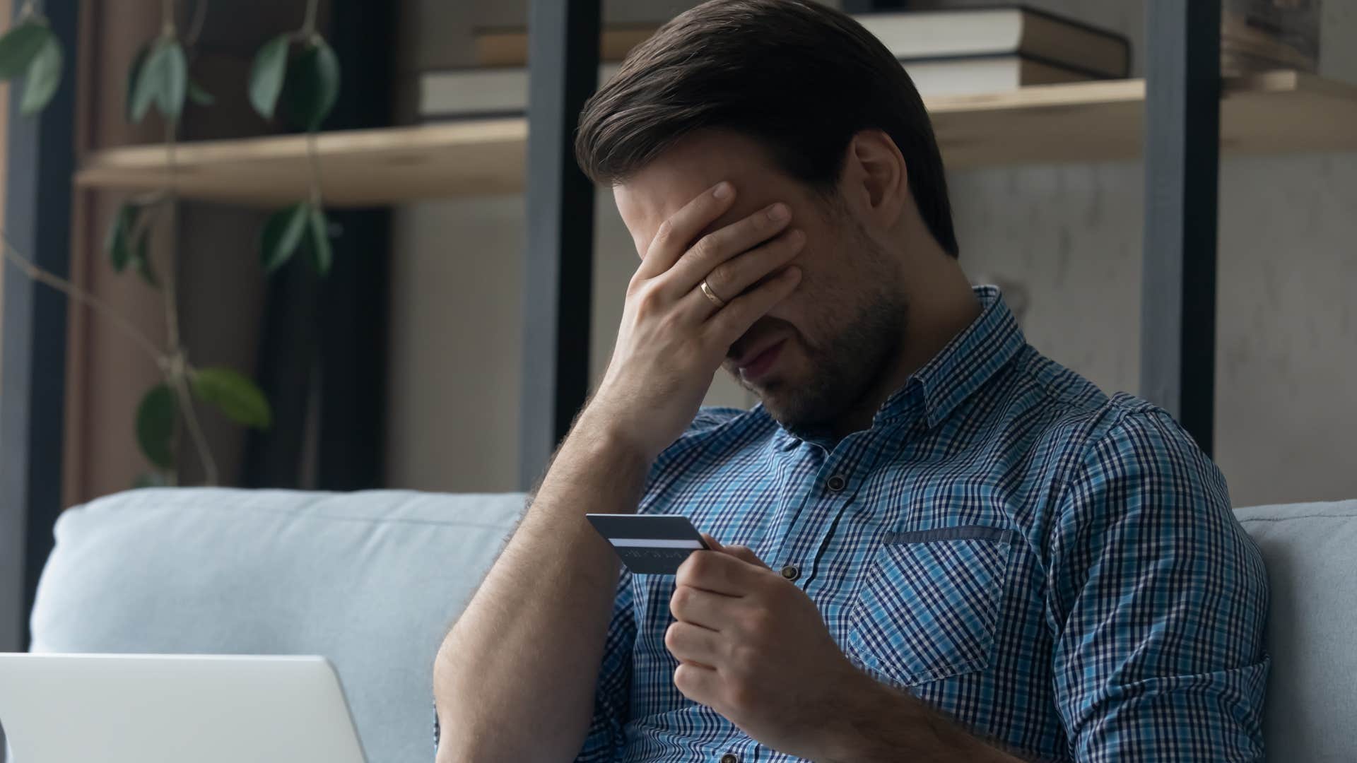 Man holding his head in his hands after overspending.