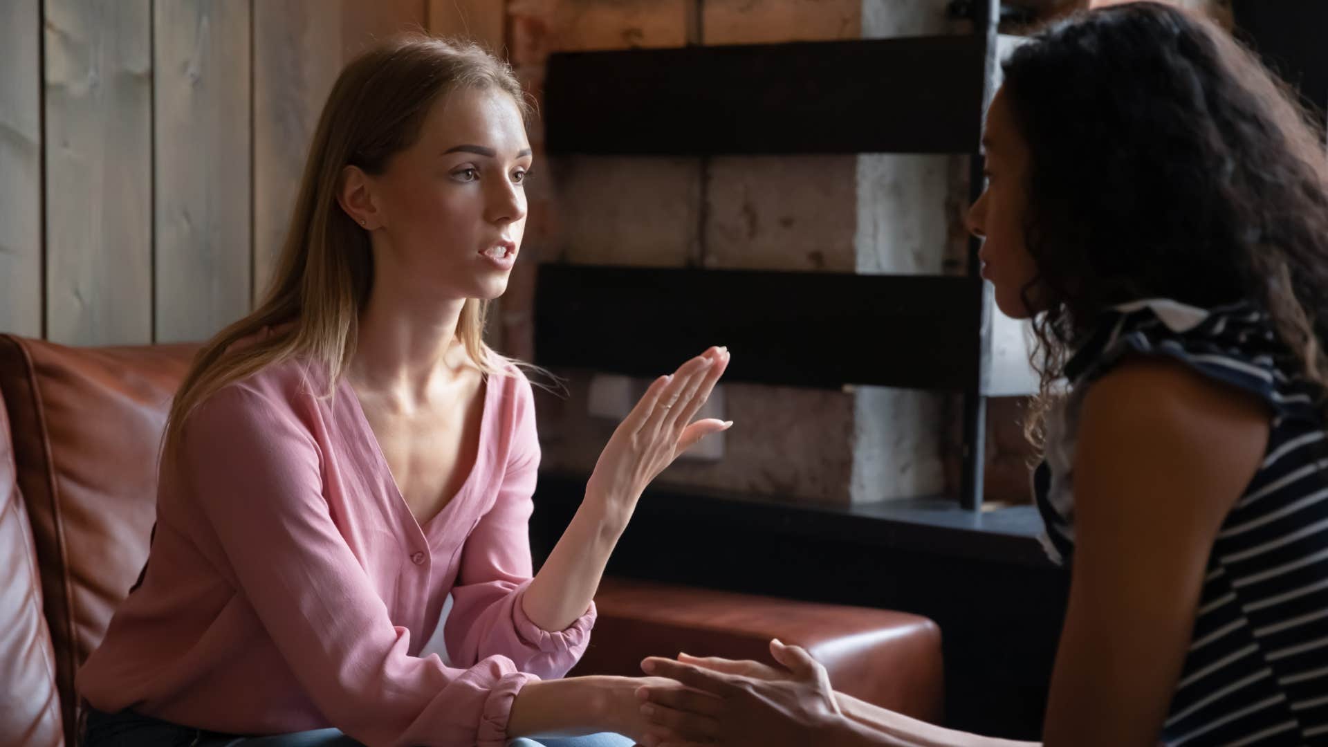 woman in pink sweater over apologizing to friend