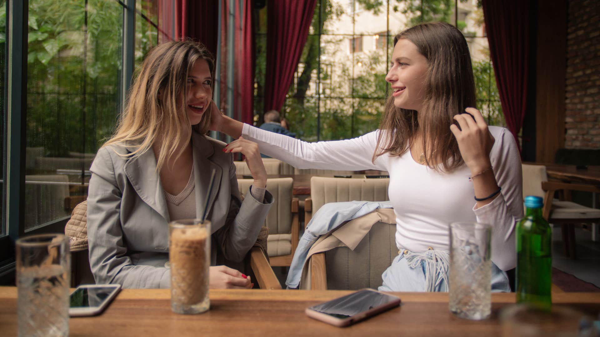 woman in pink shirt touching woman's hair while being a serial complimenter