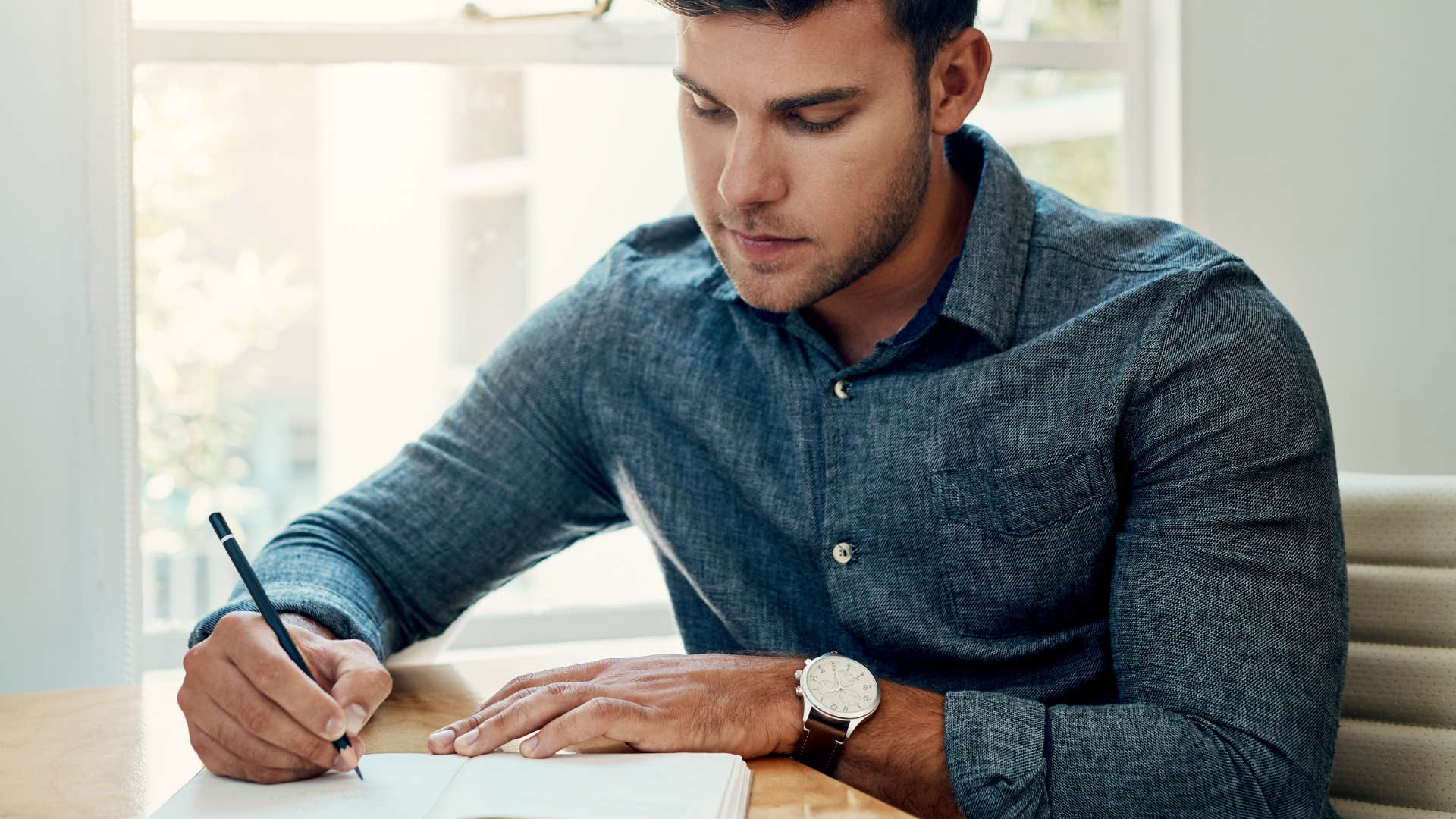 man writing a question in notebook to communicate with the universe