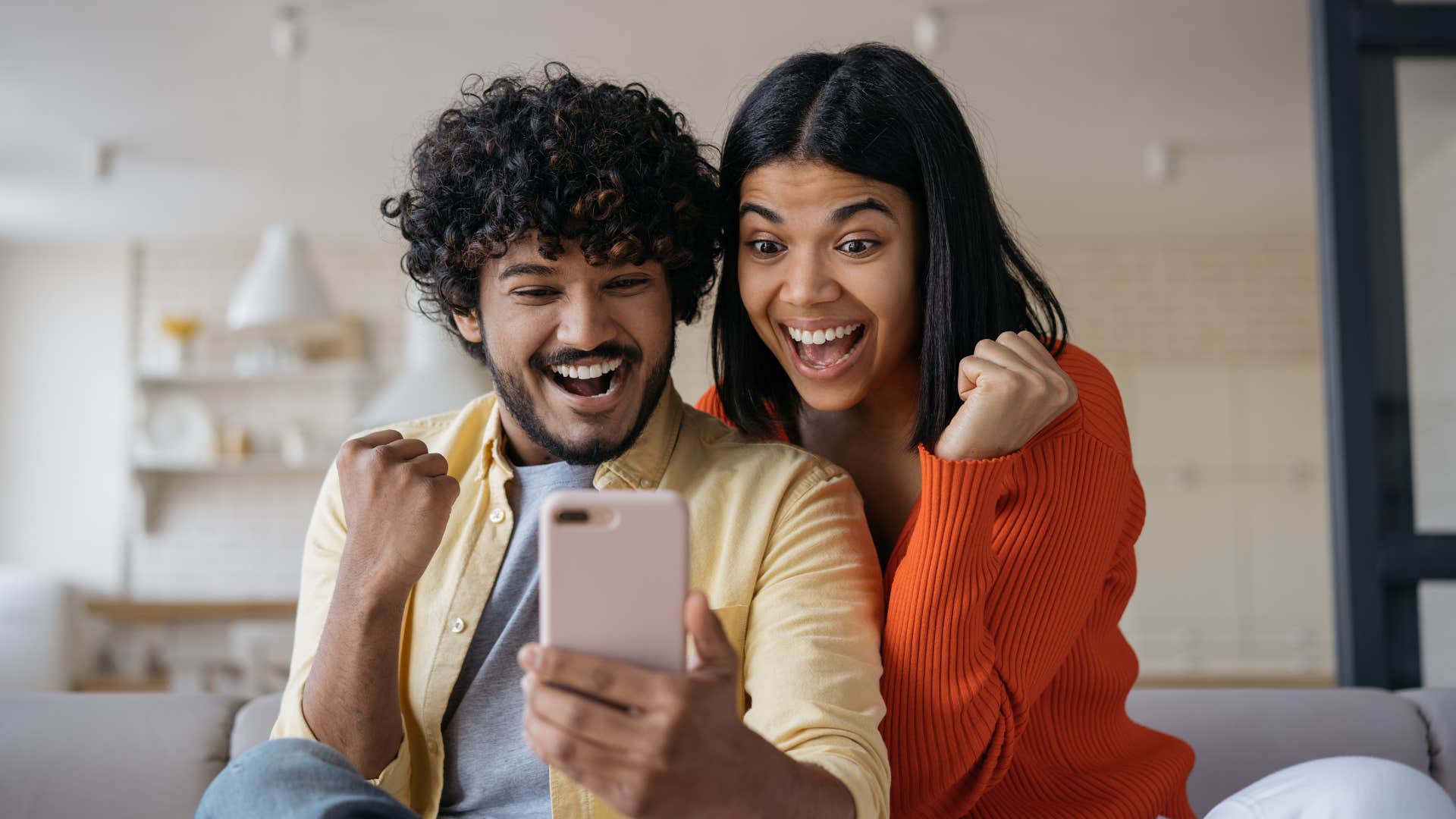 couple looking at bank balance on phone with excitement