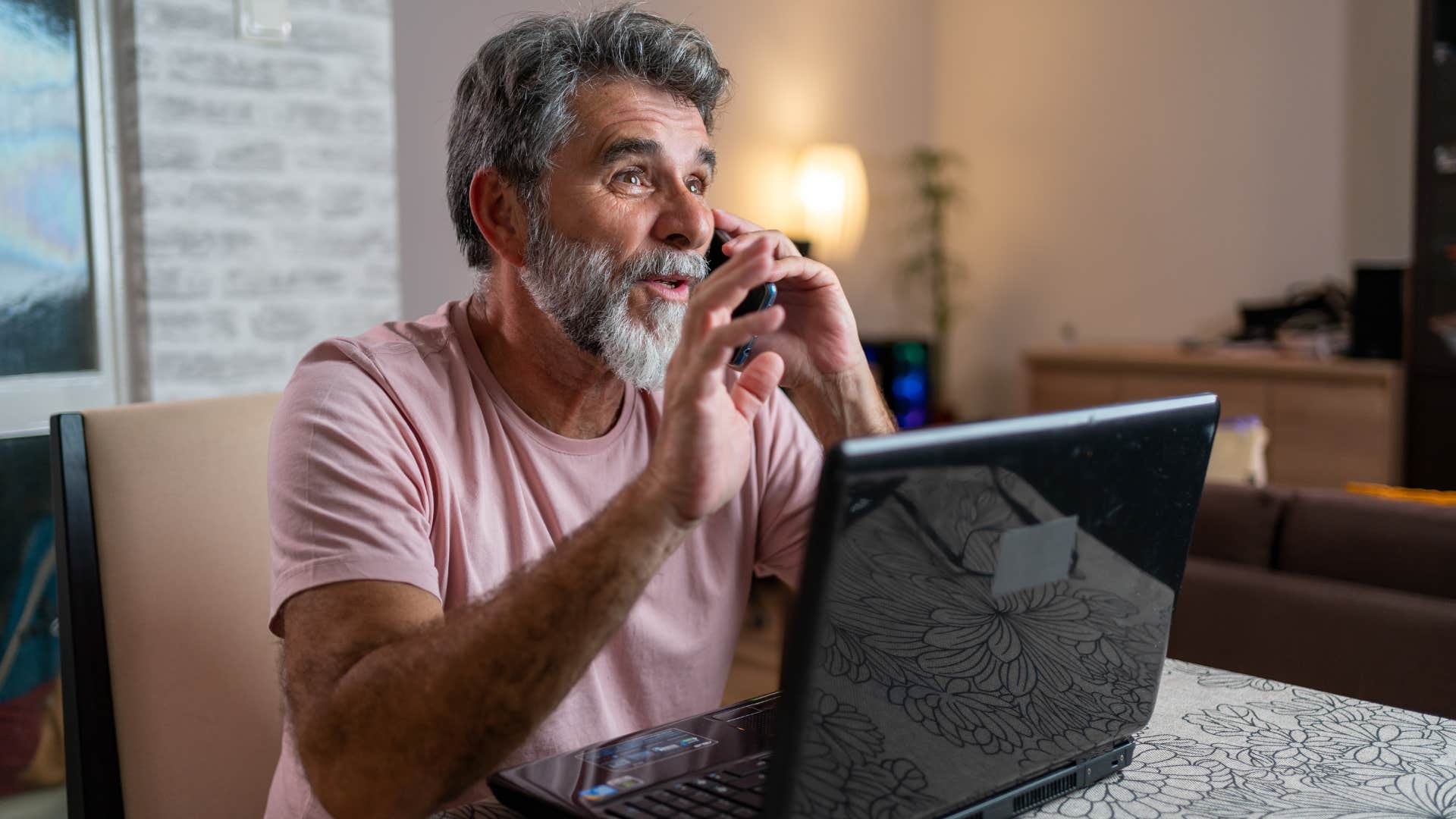 man in pink shirt saying he's gotta split as he talks on the phone in front of laptop