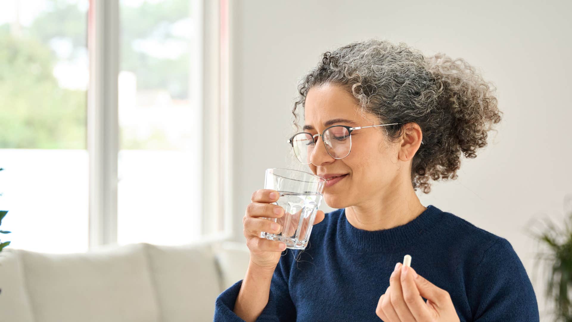 woman taking vitamins with glass of water