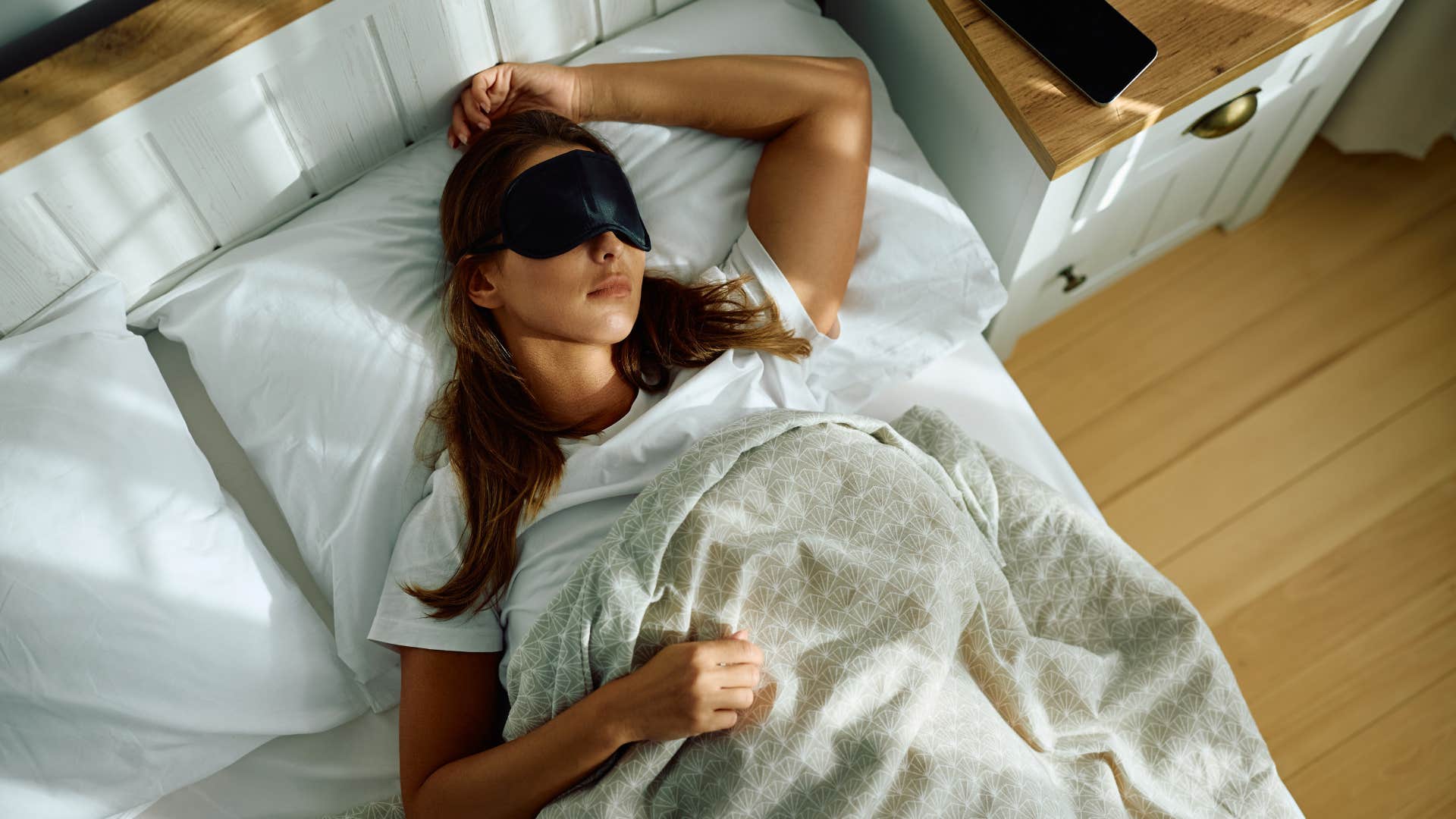 woman in eye mask having her sleep patterns change as she sleeps in