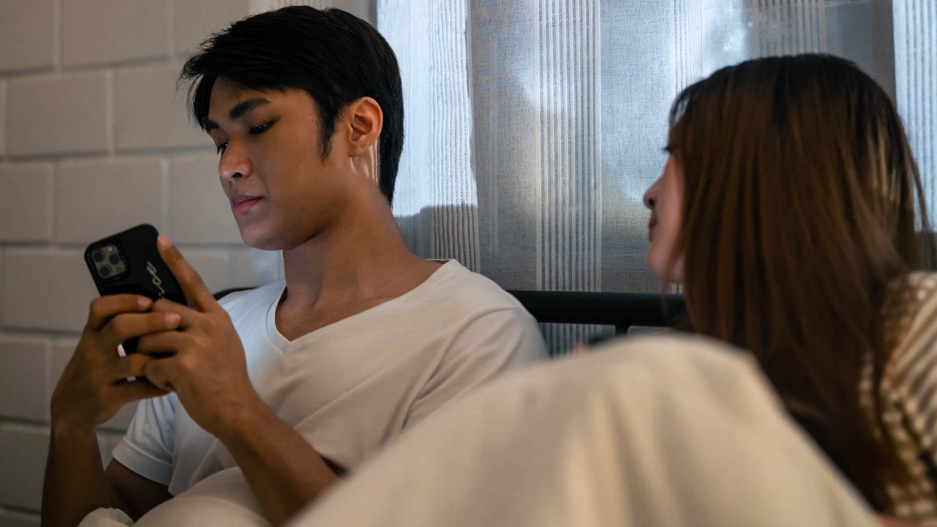 Man who's secretive turning his phone away from his wife.