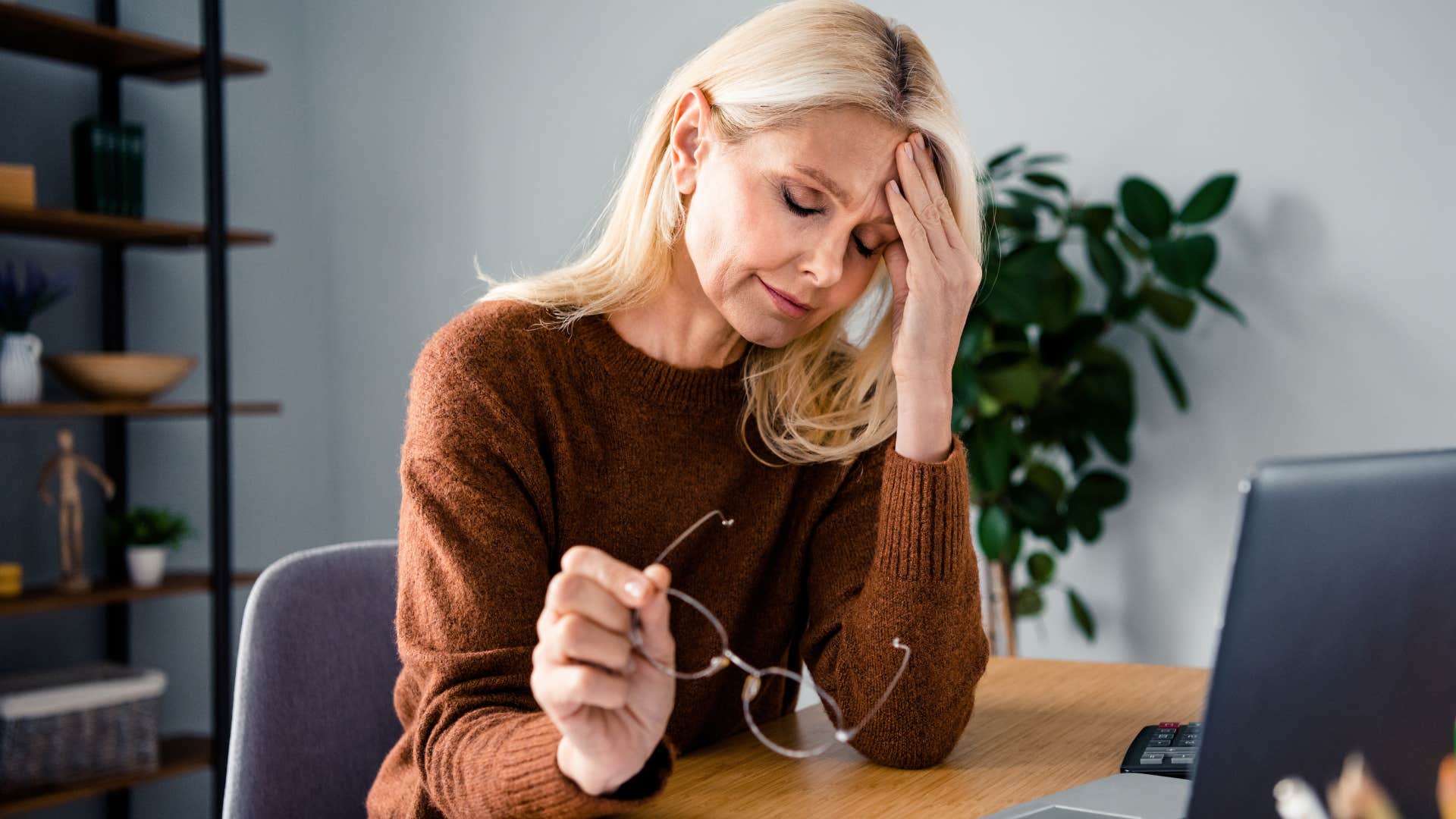 boomer woman who believes investing is for the rich holding her head