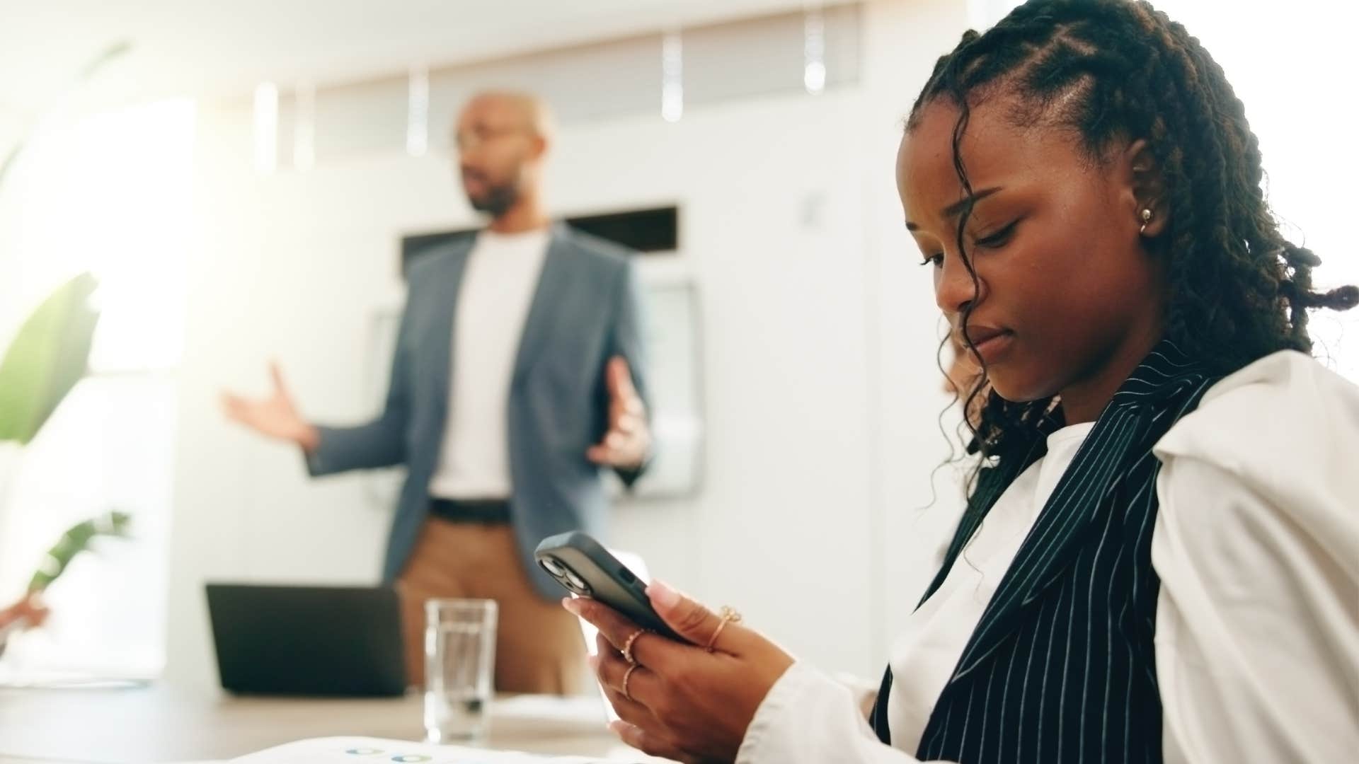 Woman who's not actively listening in a work meeting texting on her phone.